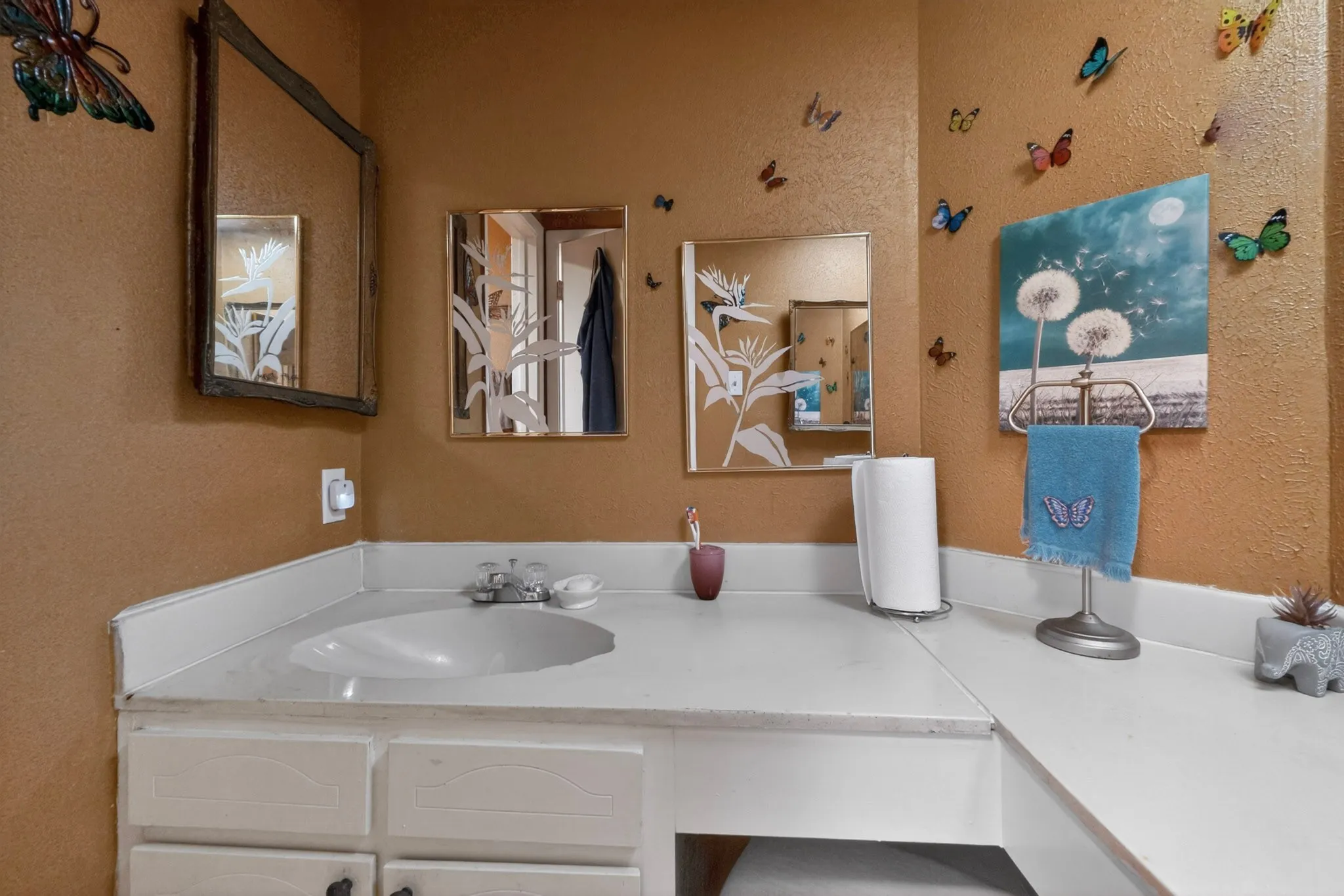 Spacious bathroom vanity featuring an integrated sink, ample counter space, white cabinetry, and multiple mirrors