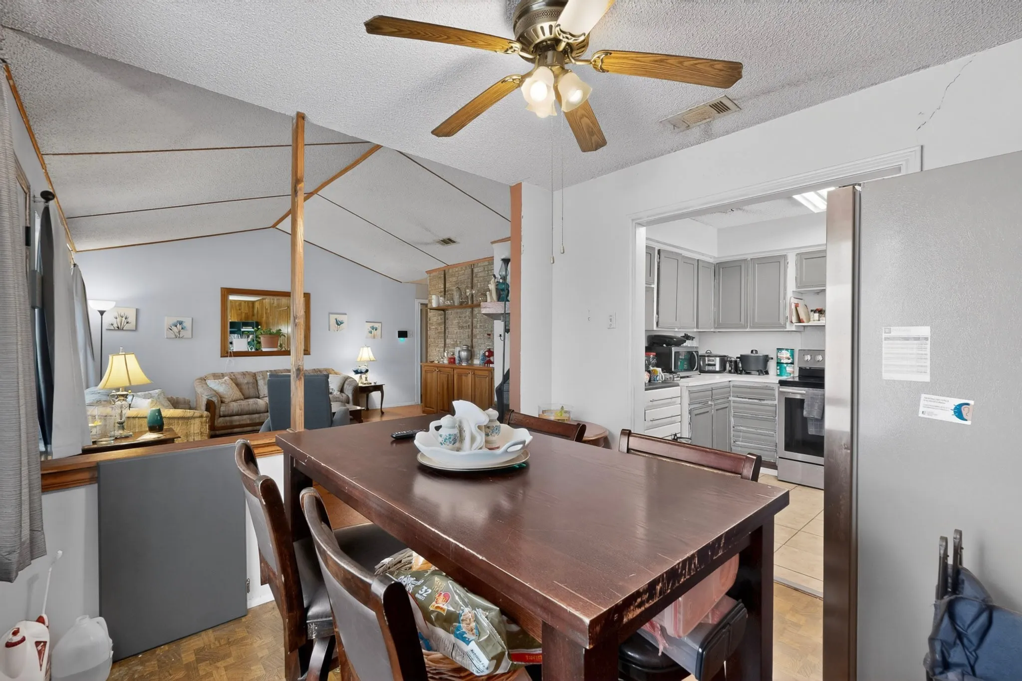 Dining area featuring wood-finish flooring, a vaulted ceiling with exposed beams, and a ceiling fan