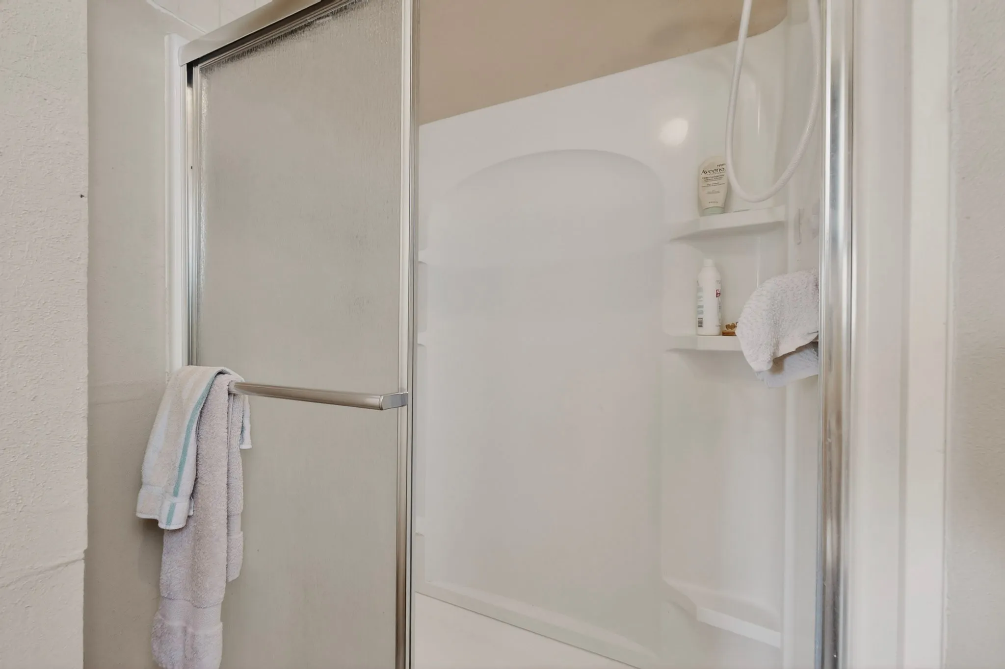 Enclosed shower with a textured glass door and a chrome handle