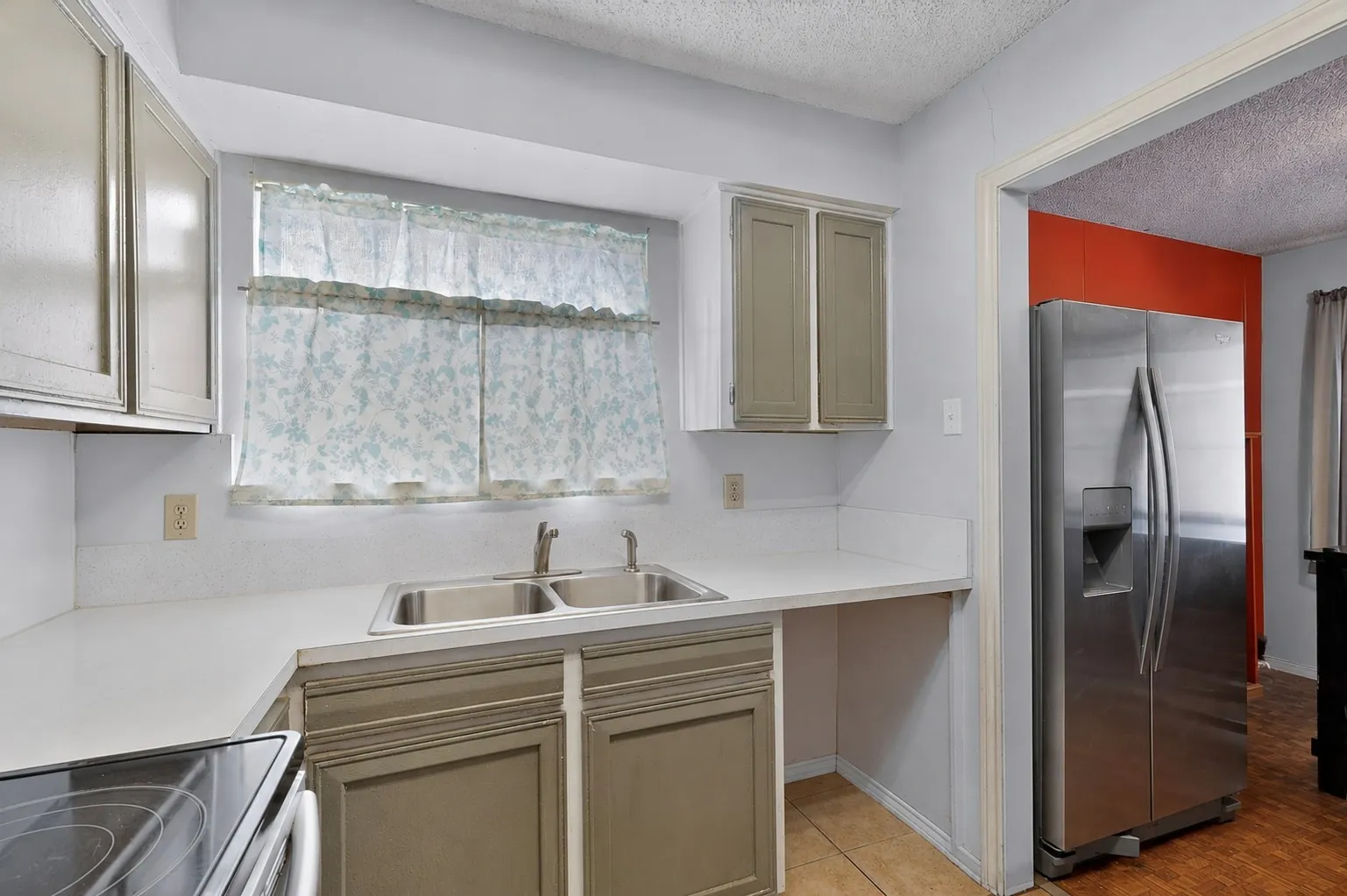Kitchen featuring a double basin stainless steel sink, light countertops, and a range of cabinetry