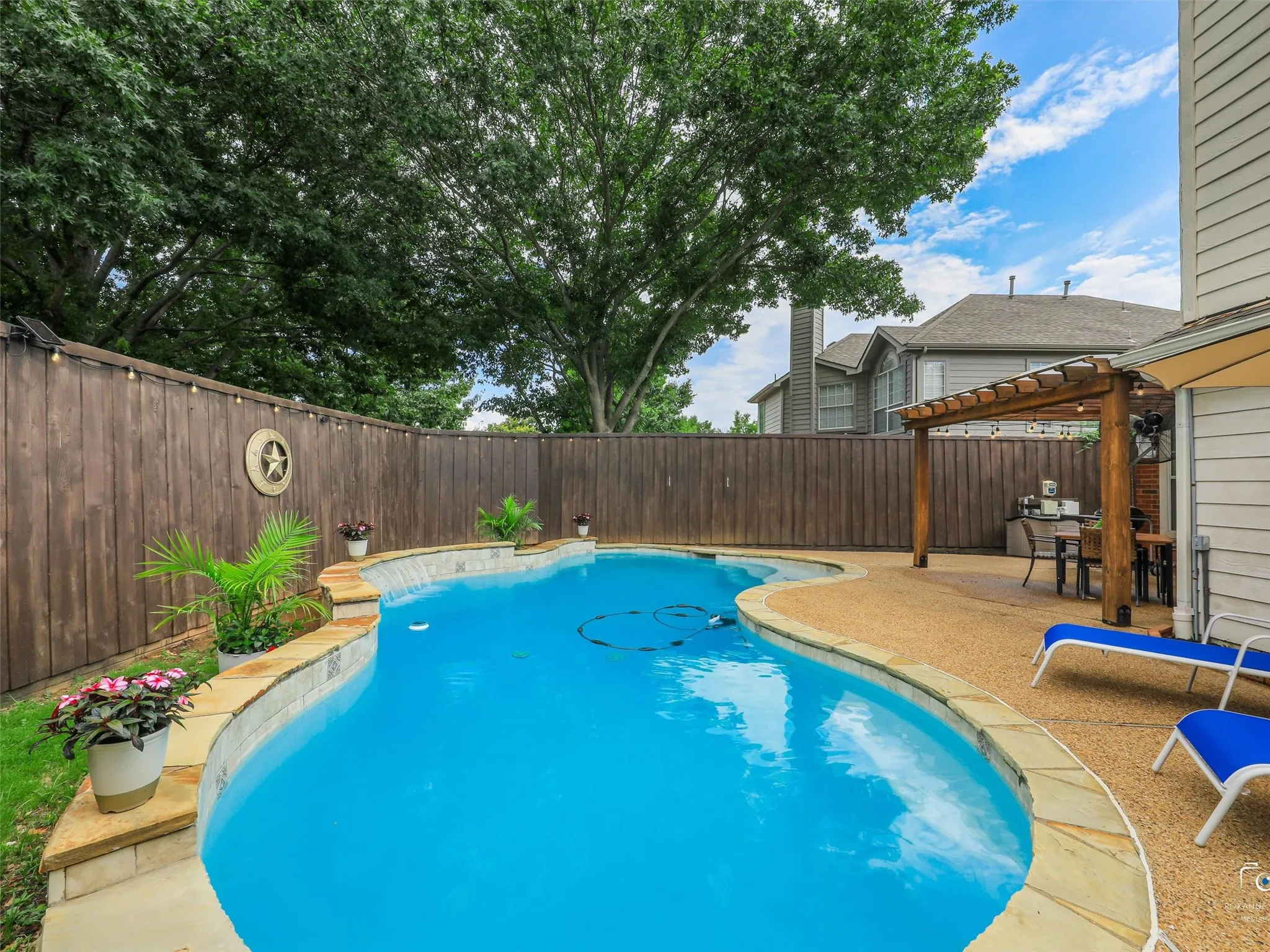 This beautifully landscaped backyard combines a sparkling pool, expansive patio, and covered pergola to create the ultimate outdoor living experience. Whether relaxing poolside or entertaining guests, this space is designed to impress.