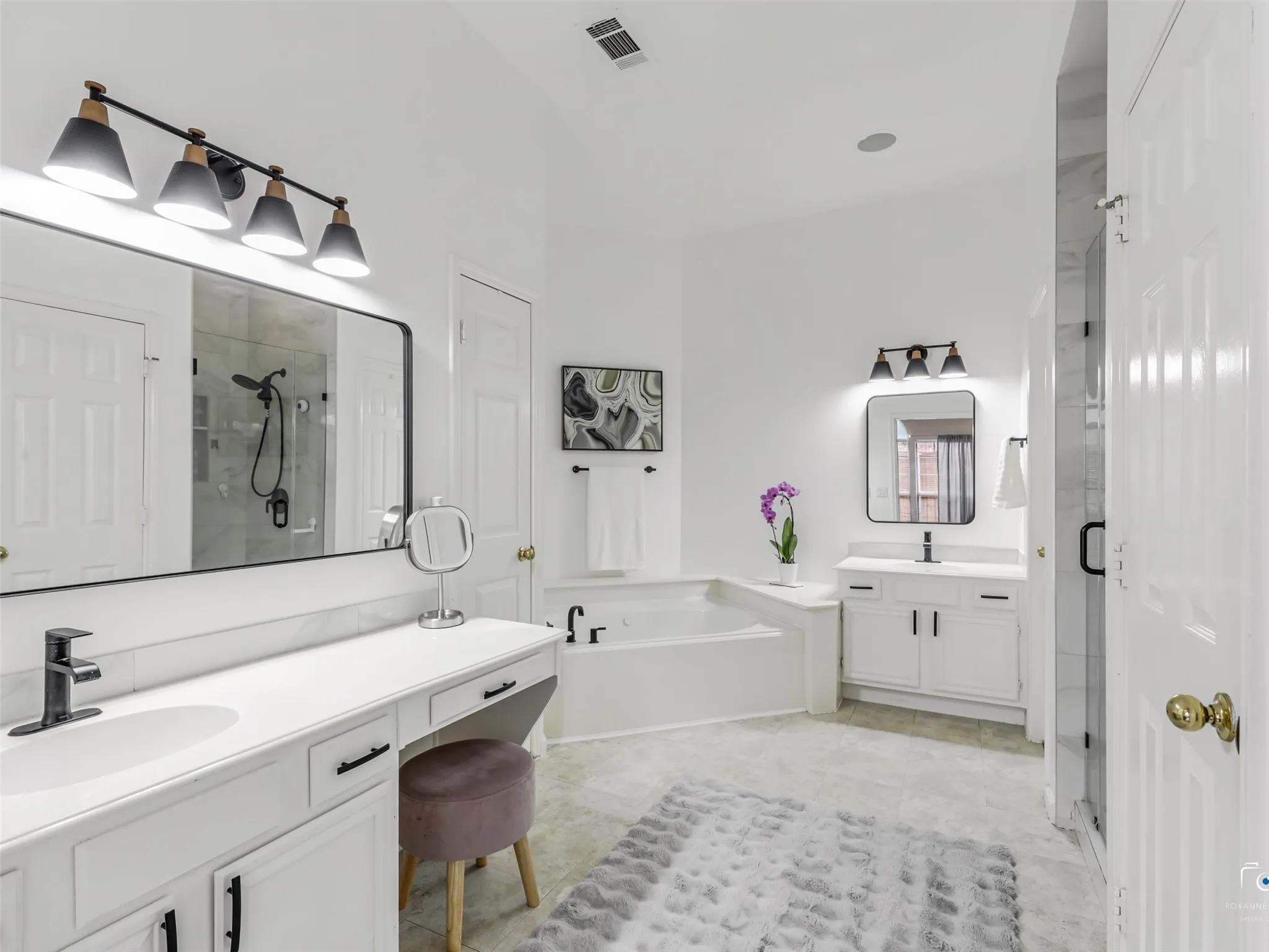 Updated and modern primary bathroom with soaking jetted tub, and separate shower. Dual vanity with sitting area.