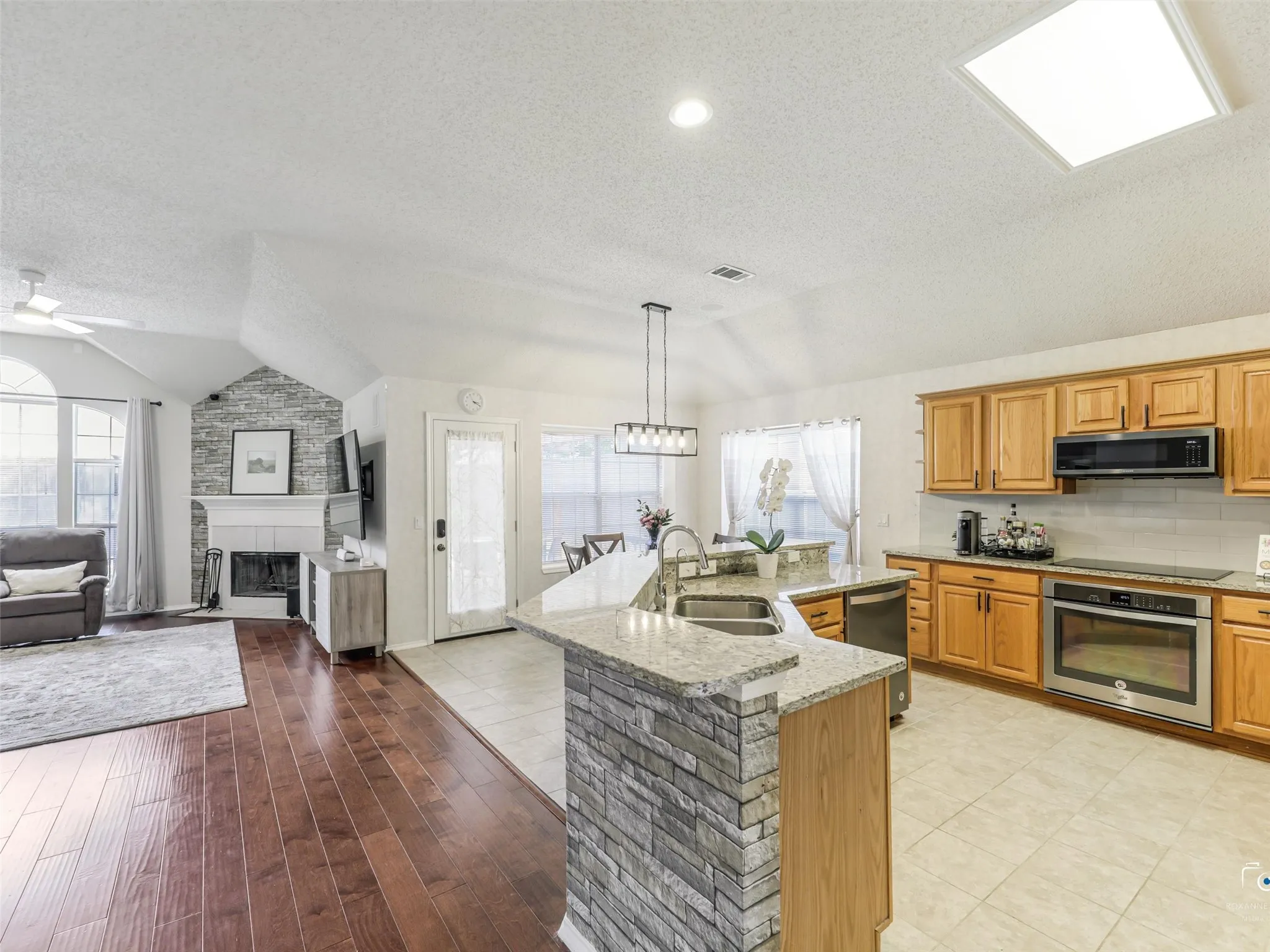 The beautifully updated kitchen offers granite countertops, abundant cabinetry, stainless steel appliances, subway tile backsplash, and generous prep space. A large peninsula provides additional seating and serves as the heart of the home.