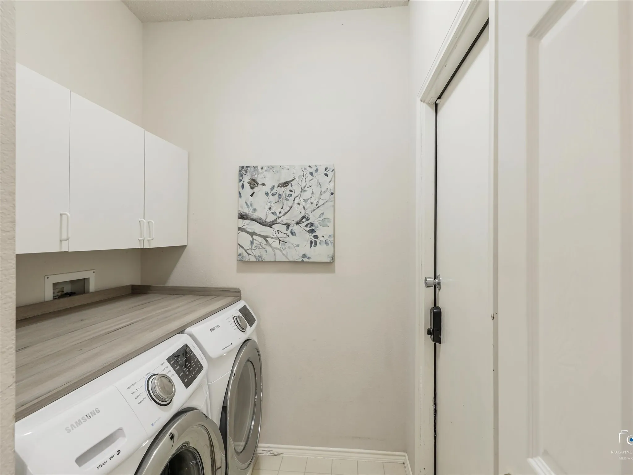 Large laundry area with upper cabinetry and nice counter space.