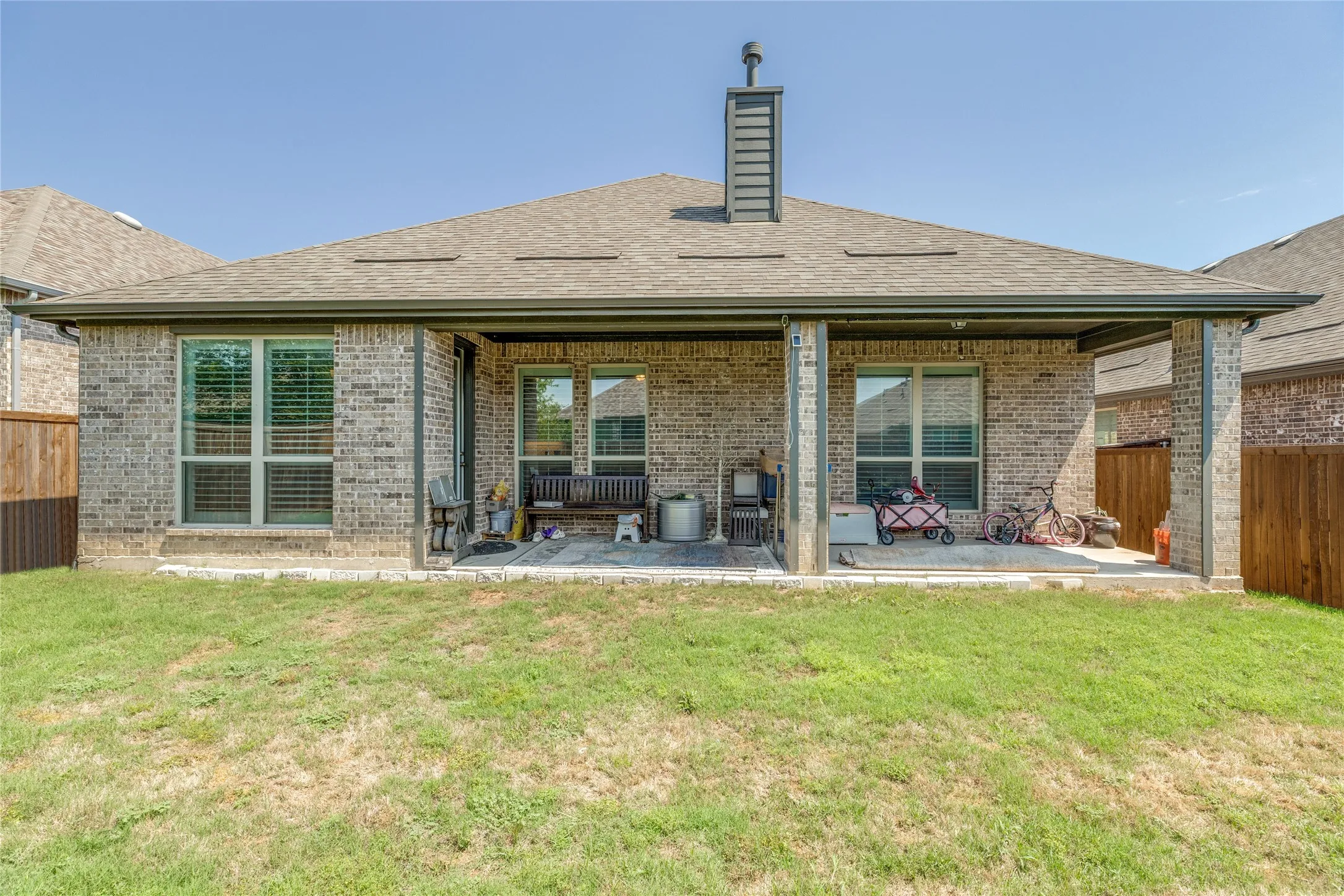 Expansive covered patio featuring brick columns, recessed lighting, and a paved surface