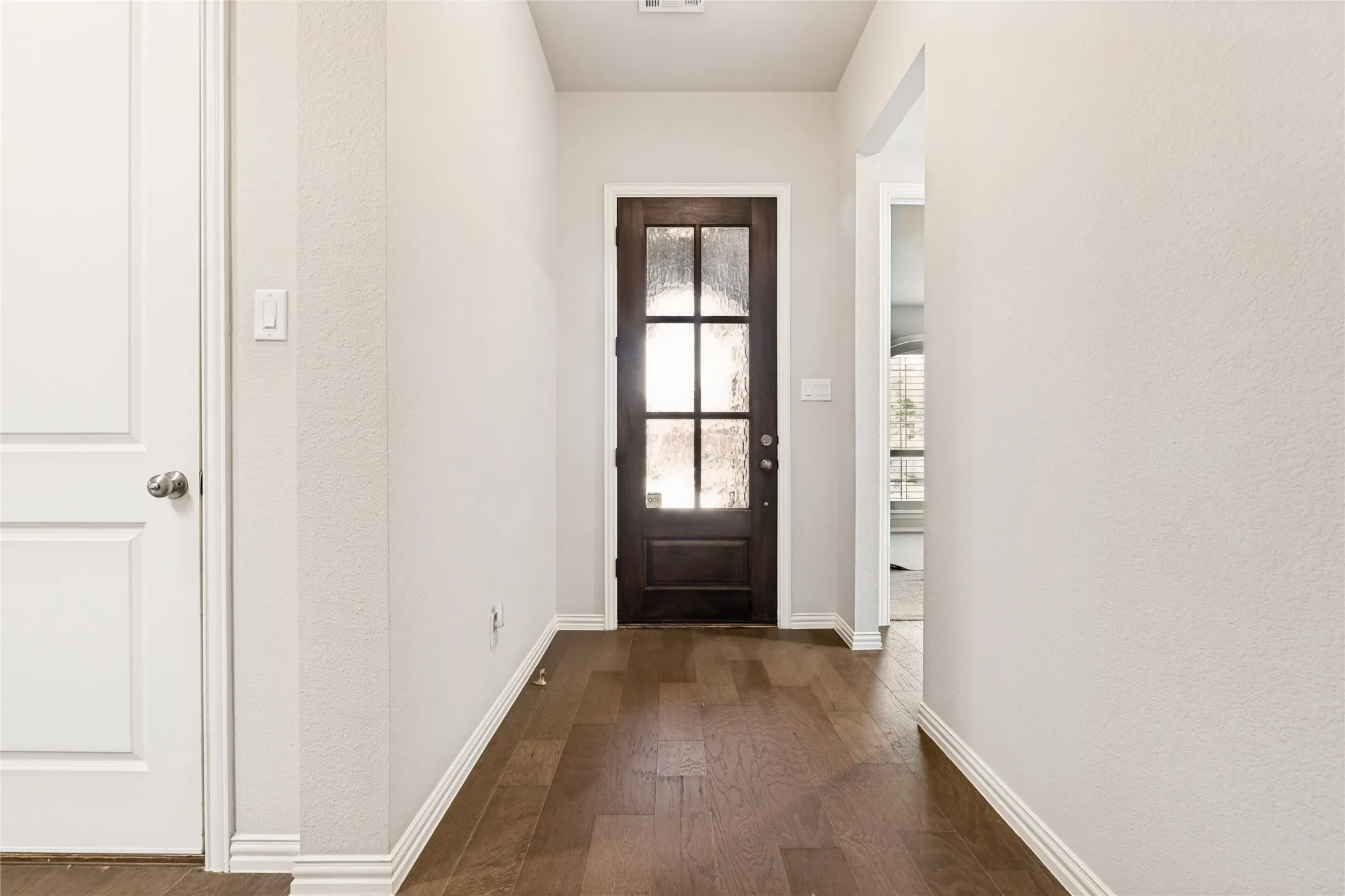 Entryway featuring a dark wood-finish door with frosted glass panels, wood-finish flooring, white baseboards, and neutral wall tones