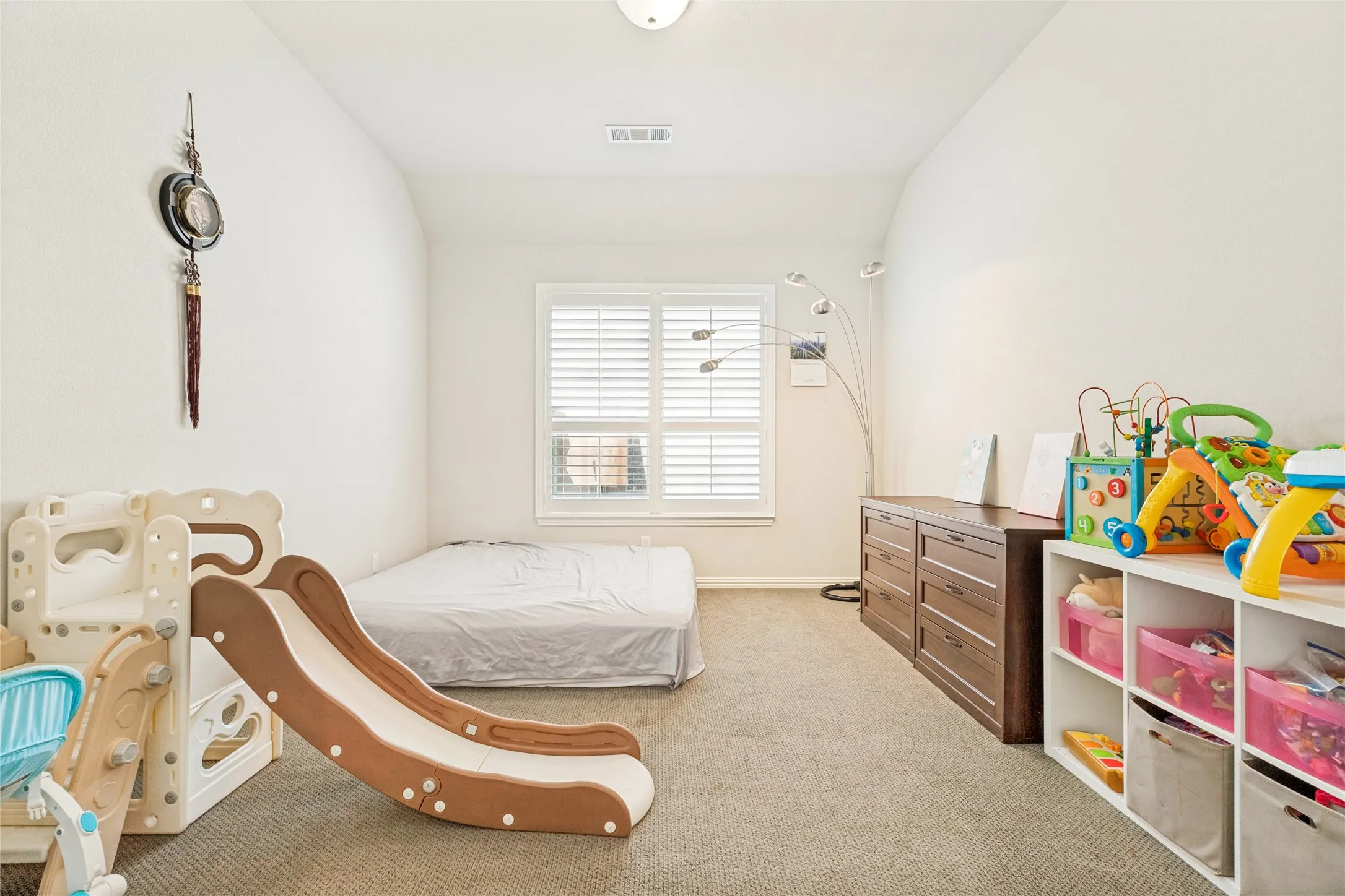 Neutral-toned room featuring a single window with white blinds, light-colored carpeting, white walls, and a ceiling light fixture