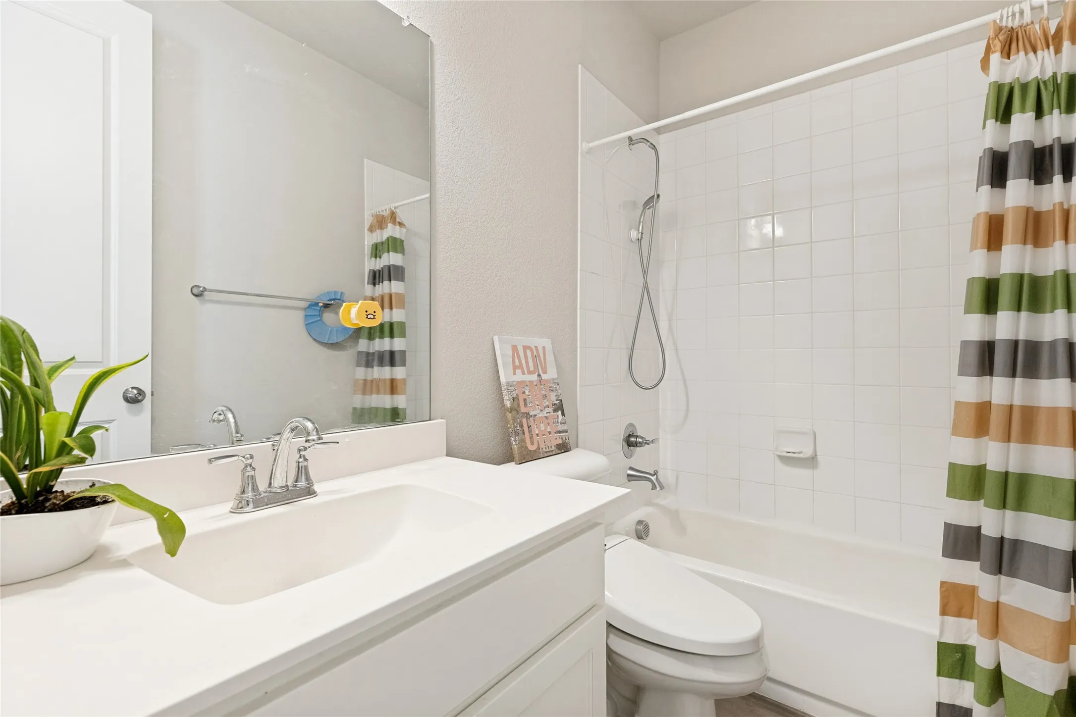 Bathroom featuring a white vanity with integrated sink, chrome faucet, and a large wall-mounted mirror