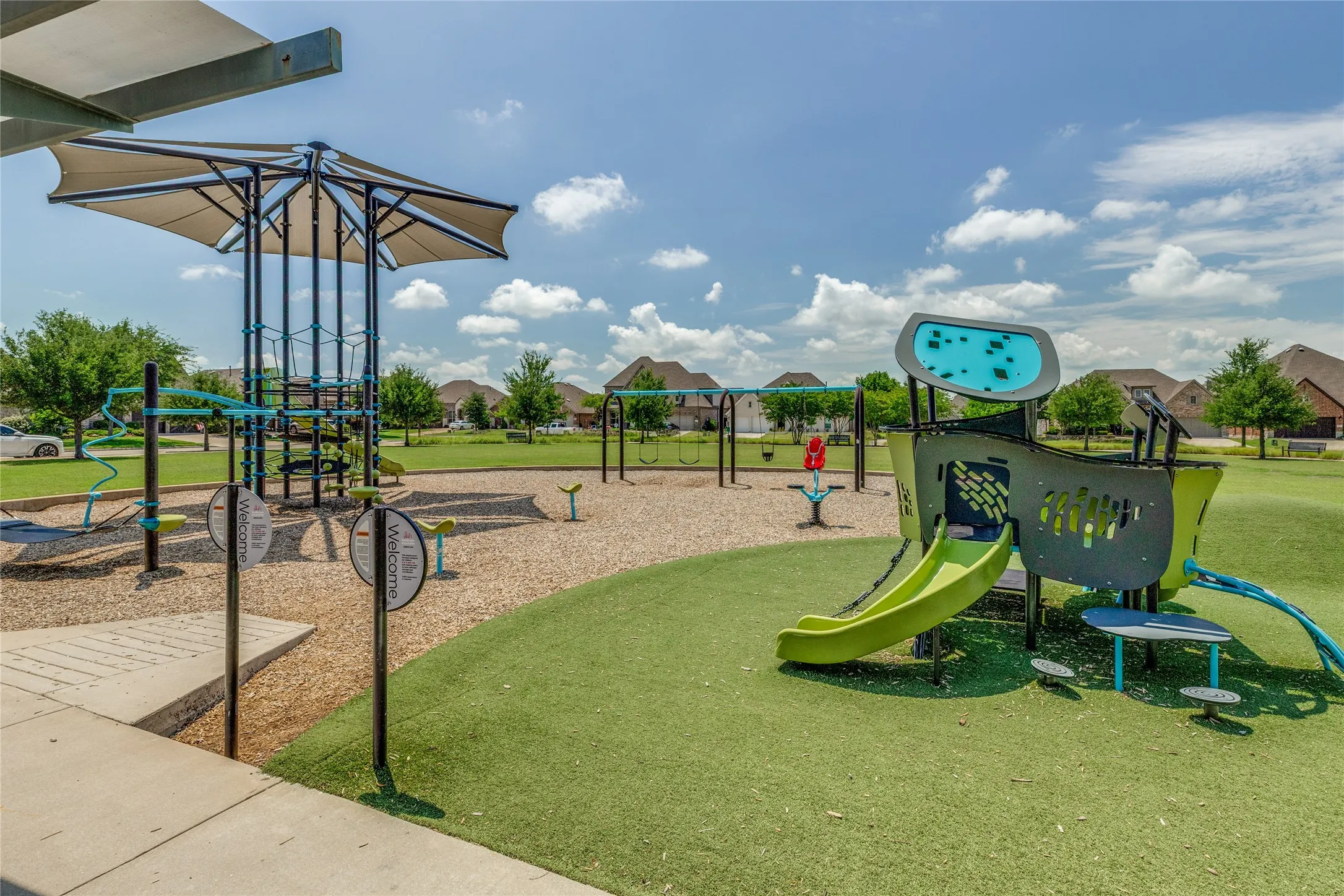 Community playground featuring varied play structures, swings, and a shaded climbing apparatus