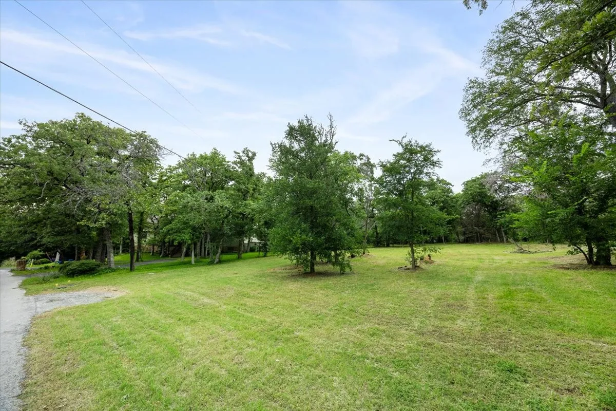 Expansive green lawn surrounded by mature trees, offering a private, natural setting