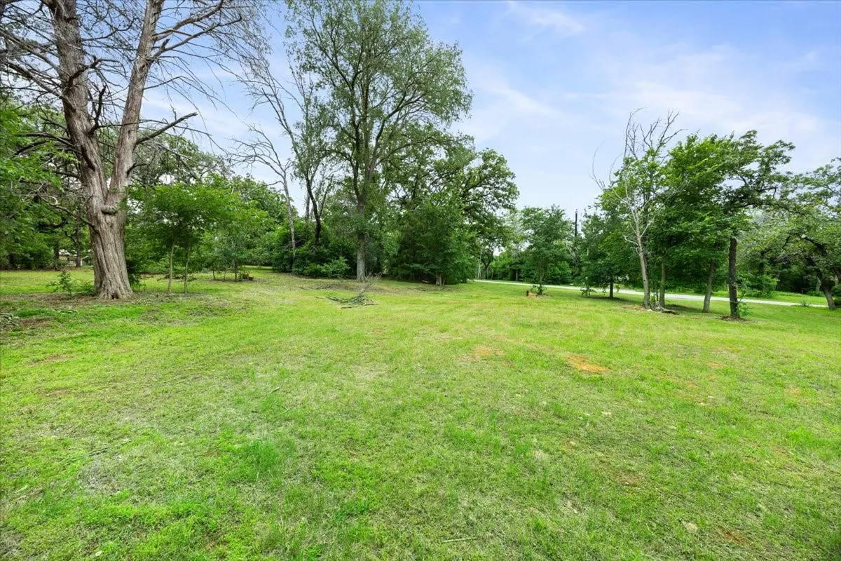 Expansive green lawn surrounded by mature trees, offering ample outdoor space