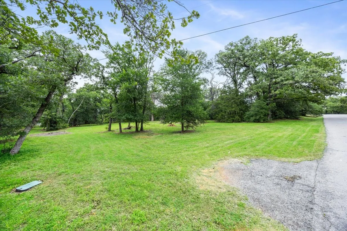 Expansive grassy lawn bordered by mature trees
