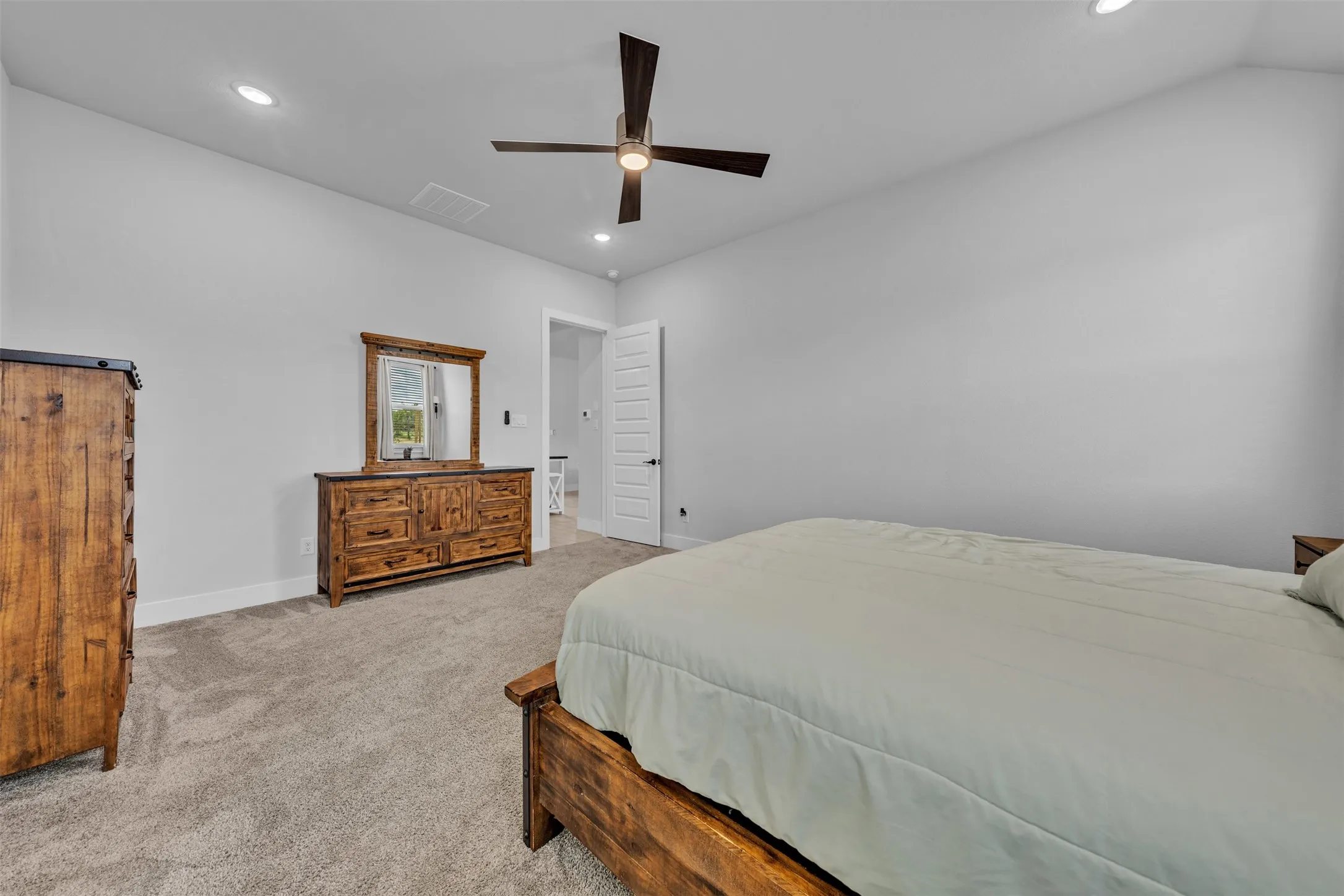 Carpeted room with a single window featuring blinds and white curtains