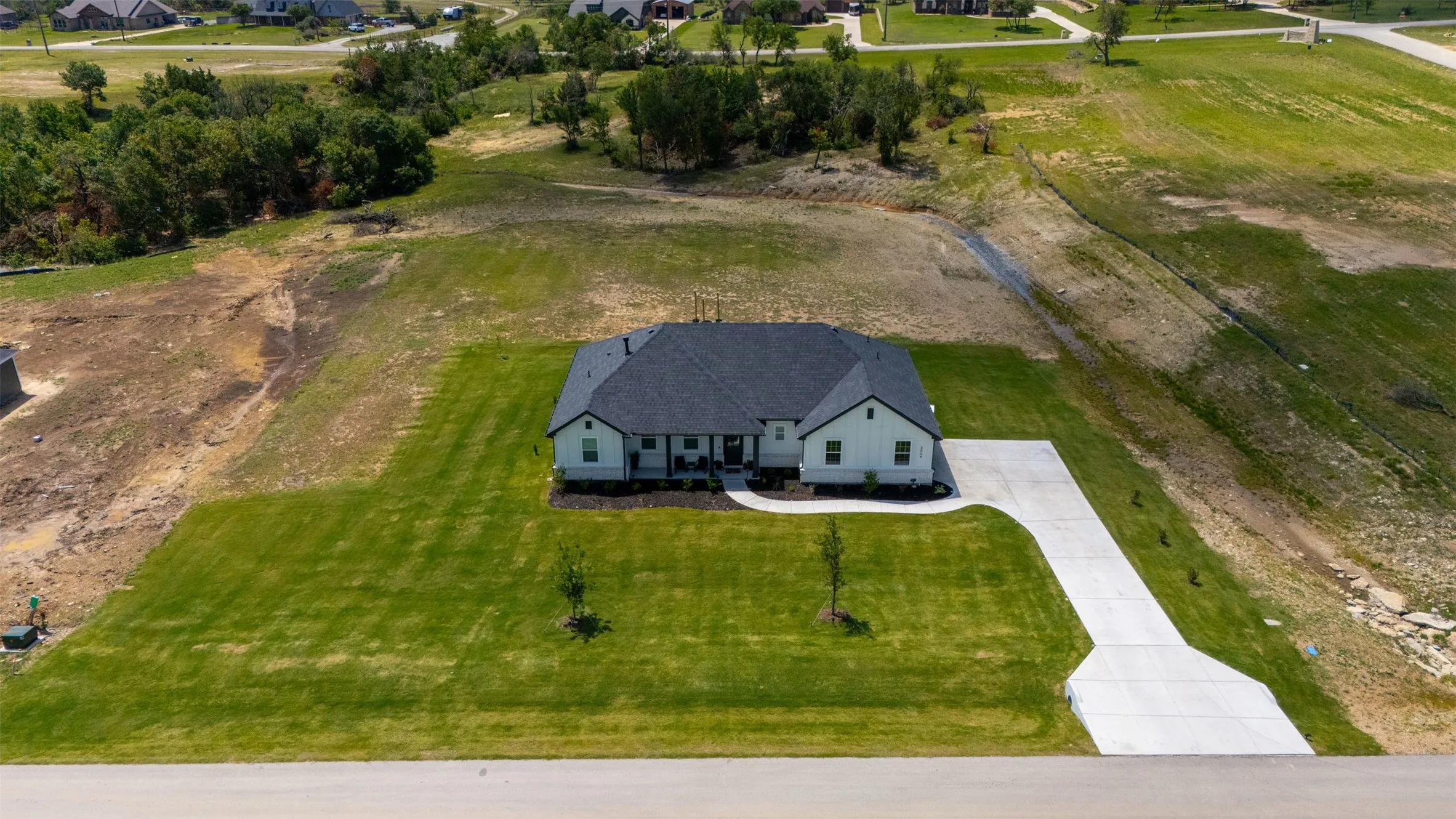 Newly constructed single-story residence with a dark shingle roof and light-colored siding