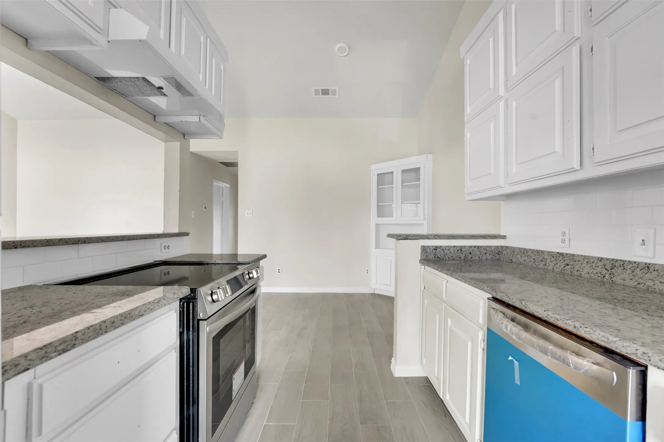 Kitchen with stainless steel range with electric cooktop, dishwasher, white cabinets, and light stone countertops