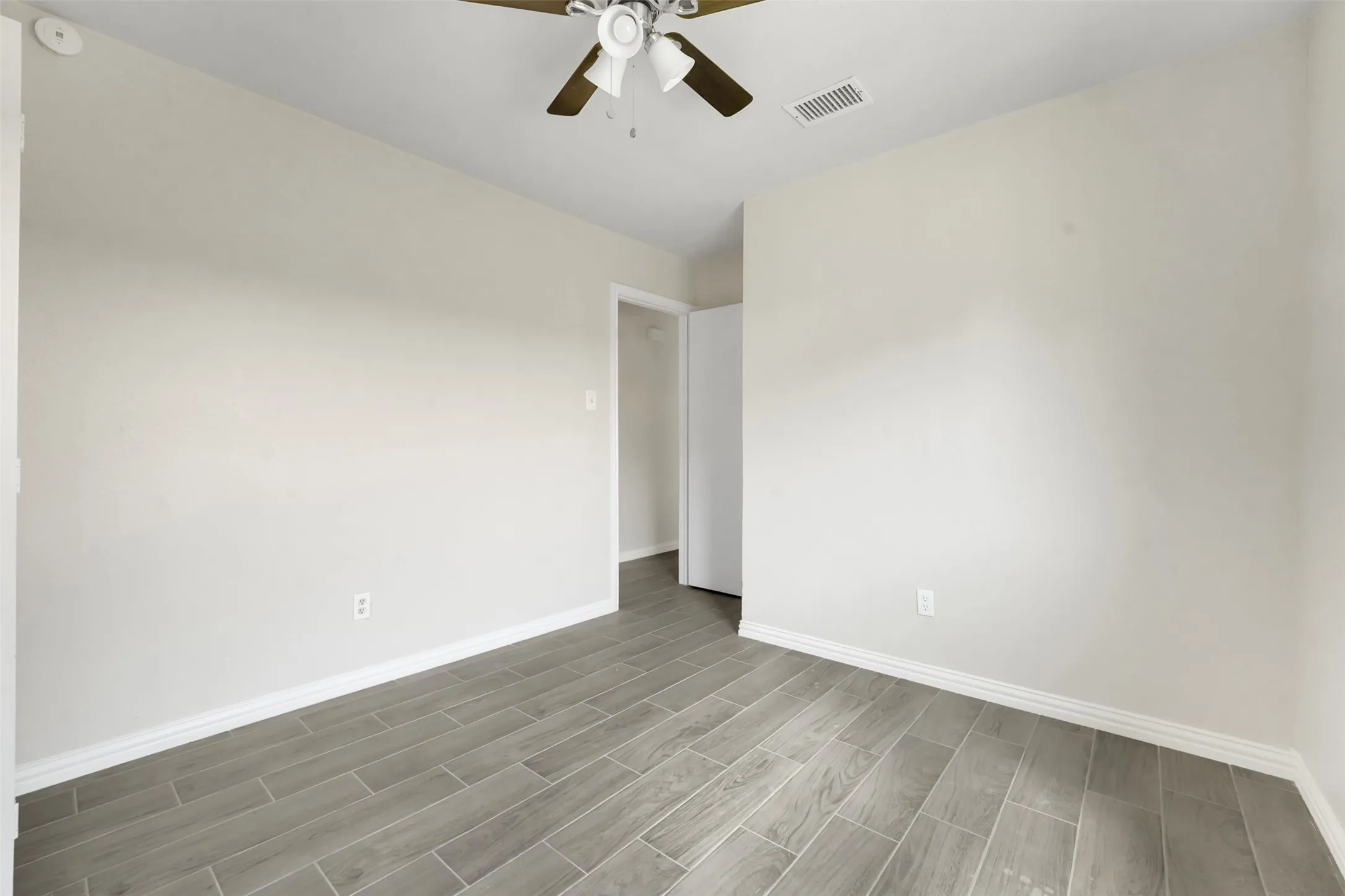 Unfurnished room with wood finished floors, ceiling fan, and a smoke detector