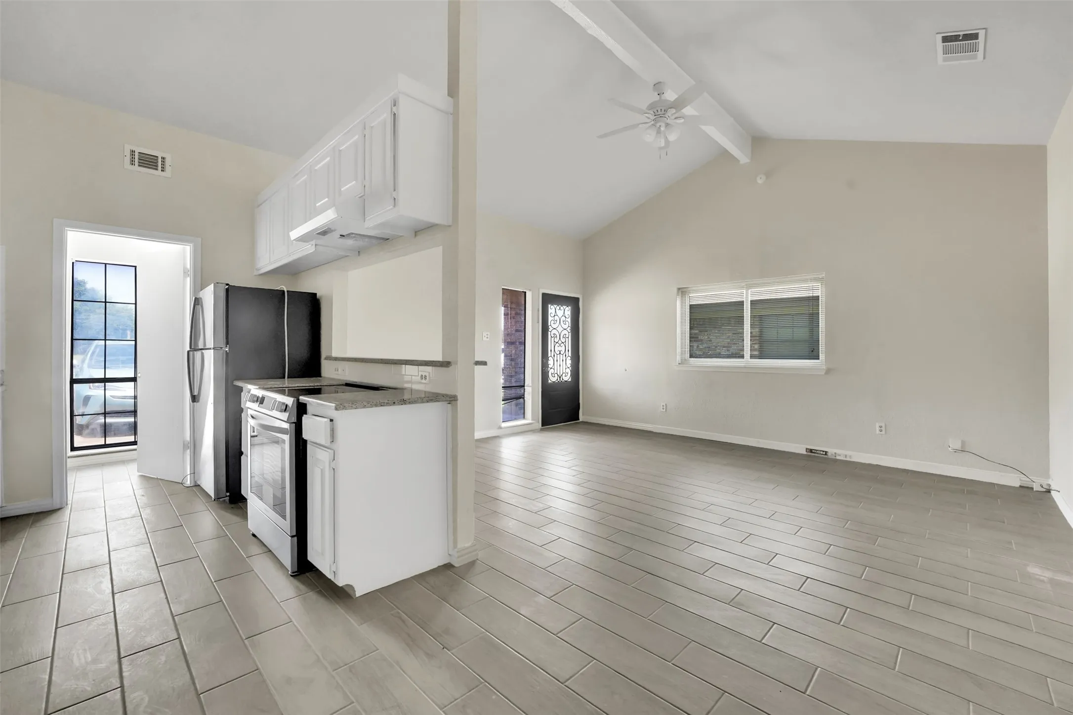 Kitchen featuring stainless steel appliances, ceiling fan, beamed ceiling, white cabinetry, and open floor plan