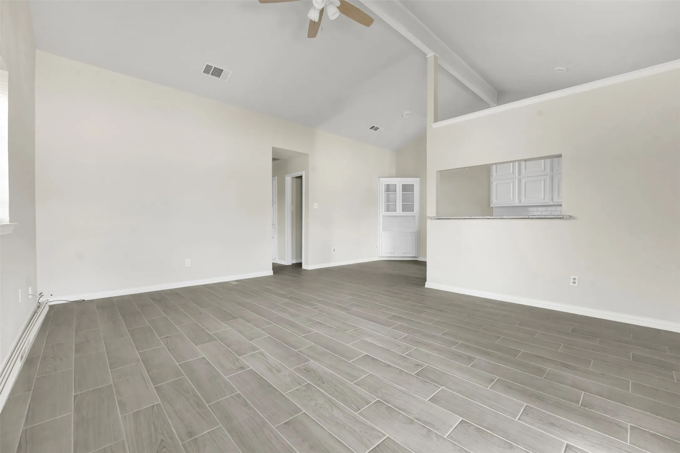 Spare room featuring a ceiling fan, beamed ceiling, wood finished floors, and high vaulted ceiling