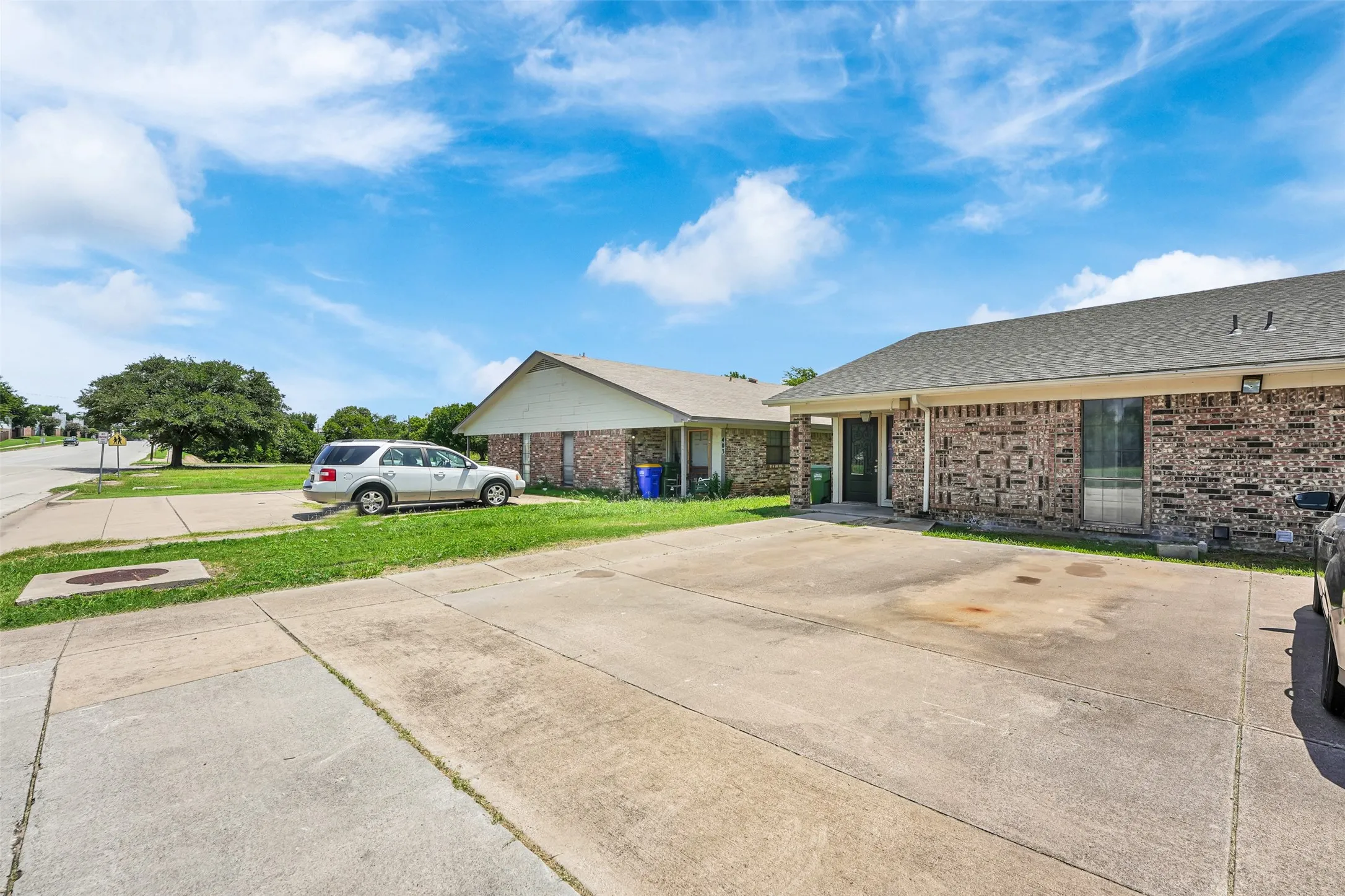Ranch-style home with brick siding, a front yard, a shingled roof, and driveway