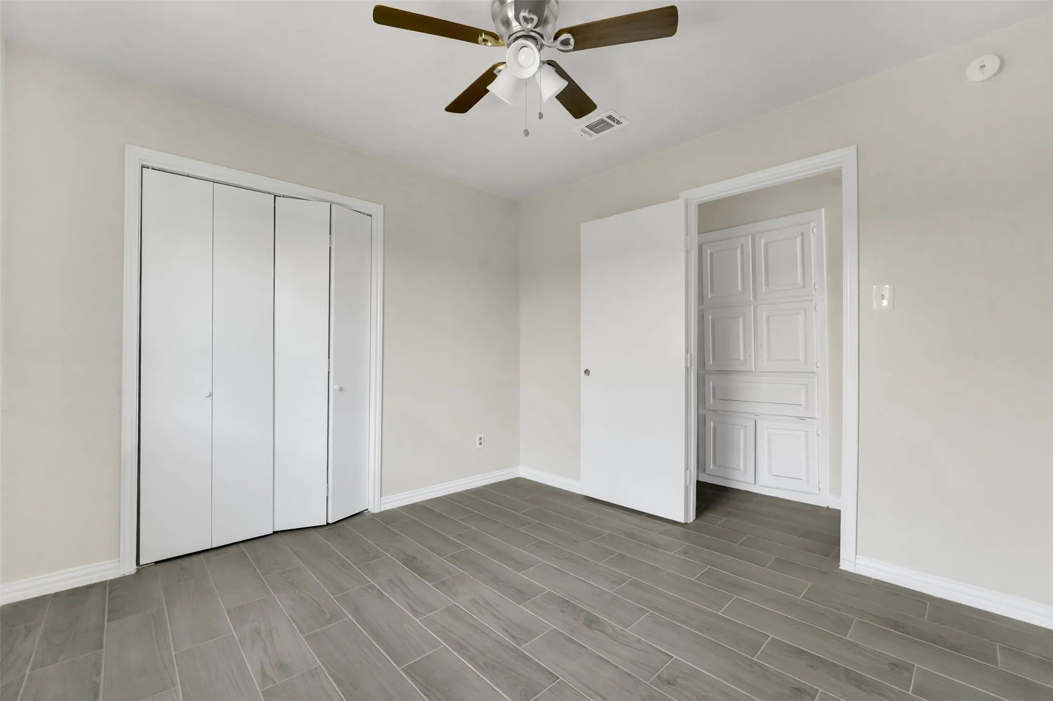 Unfurnished bedroom with wood tiled floors, a closet, and ceiling fan