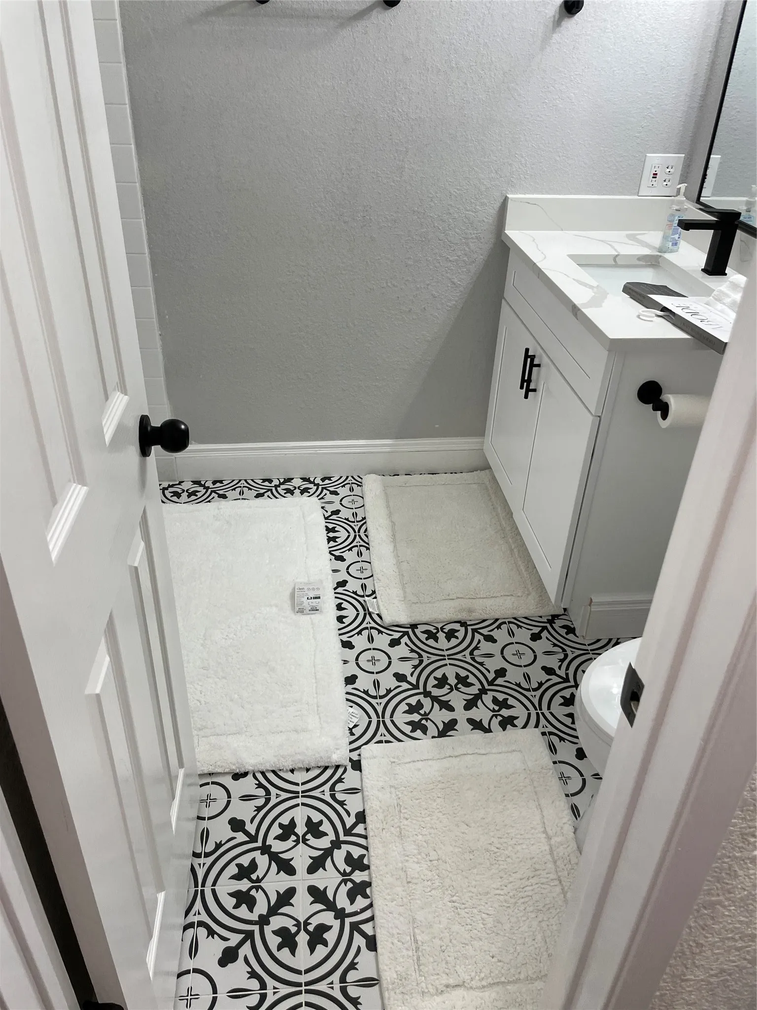 Bathroom featuring patterned floor tiles, a white vanity with a countertop sink, and a wall-mounted mirror