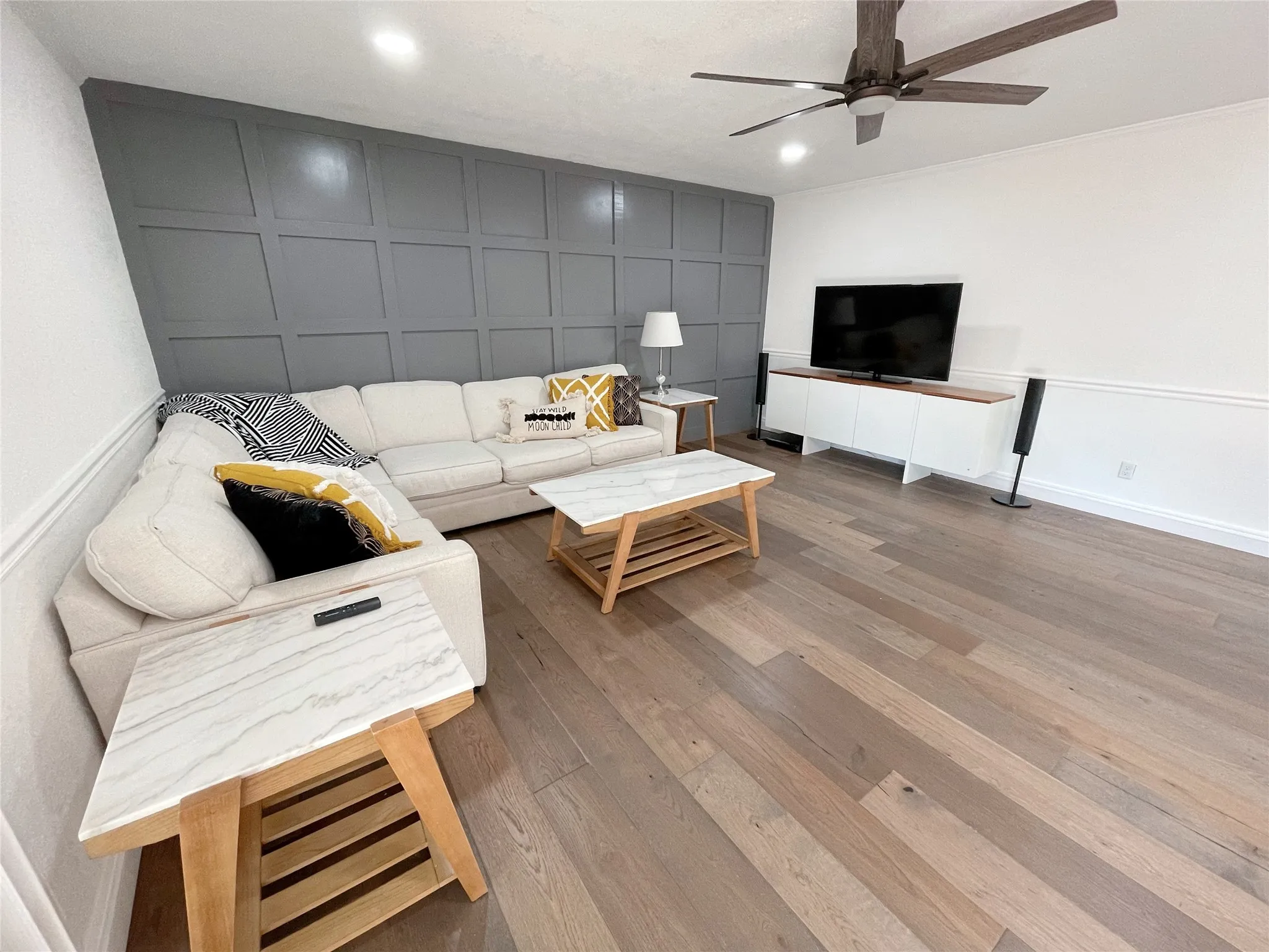 Spacious living area featuring wide-plank wood-finish flooring, a contemporary ceiling fan, and recessed lighting