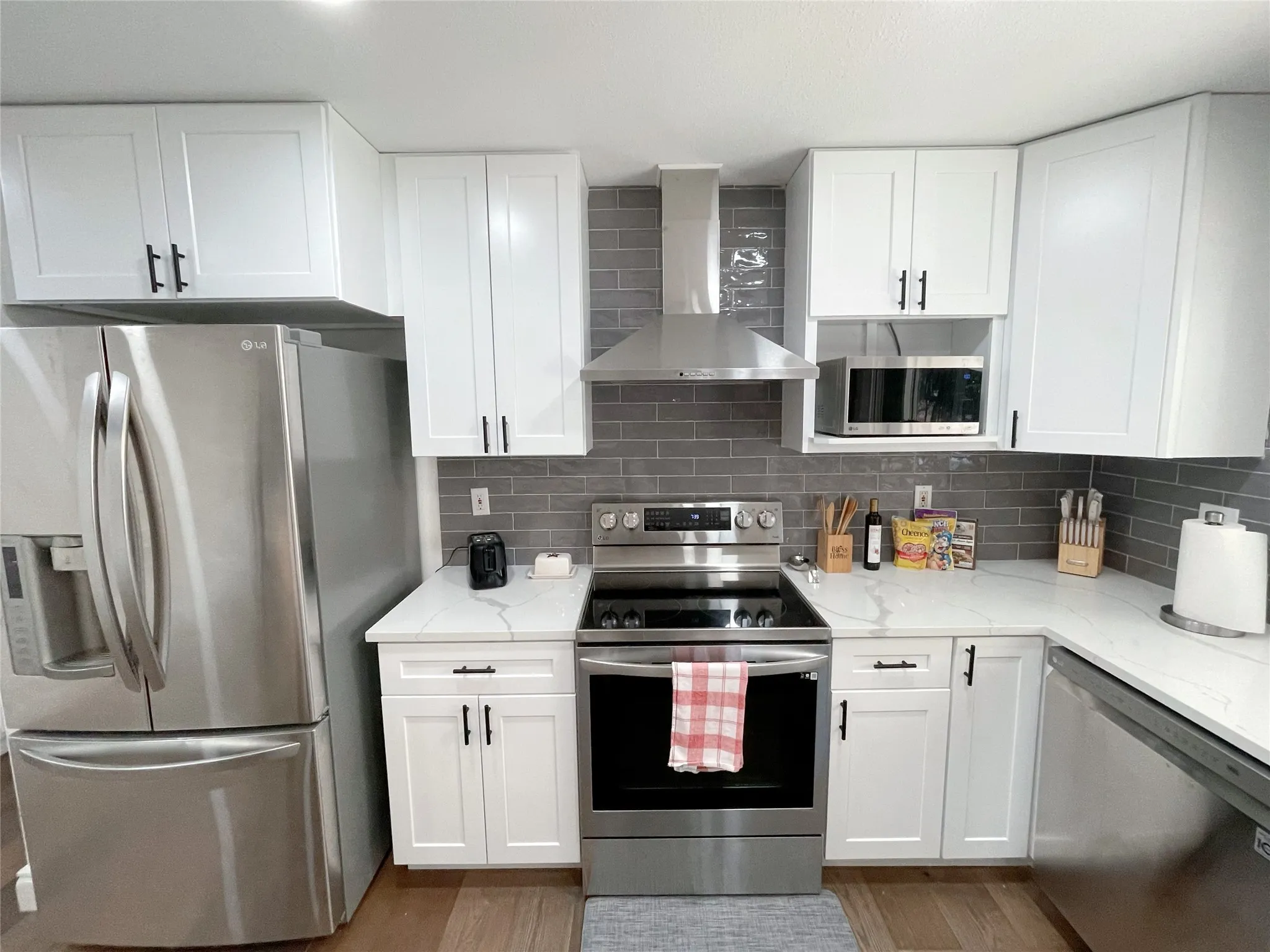 Contemporary kitchen featuring white shaker cabinetry, stainless steel appliances, a subway tile backsplash, and stone-look countertops