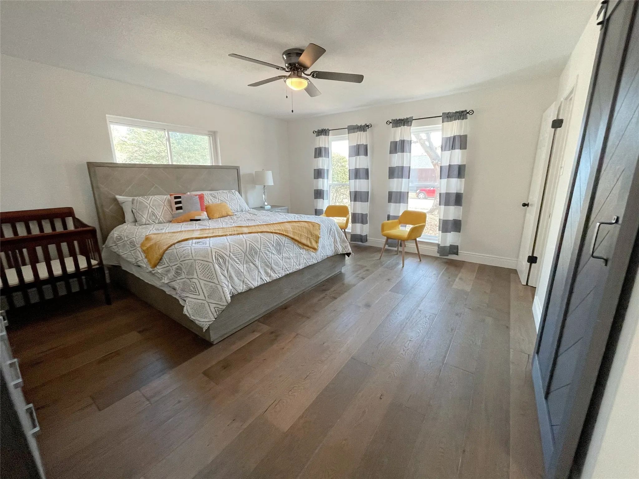 Spacious interior featuring wood-finish flooring, a contemporary ceiling fan, and white walls