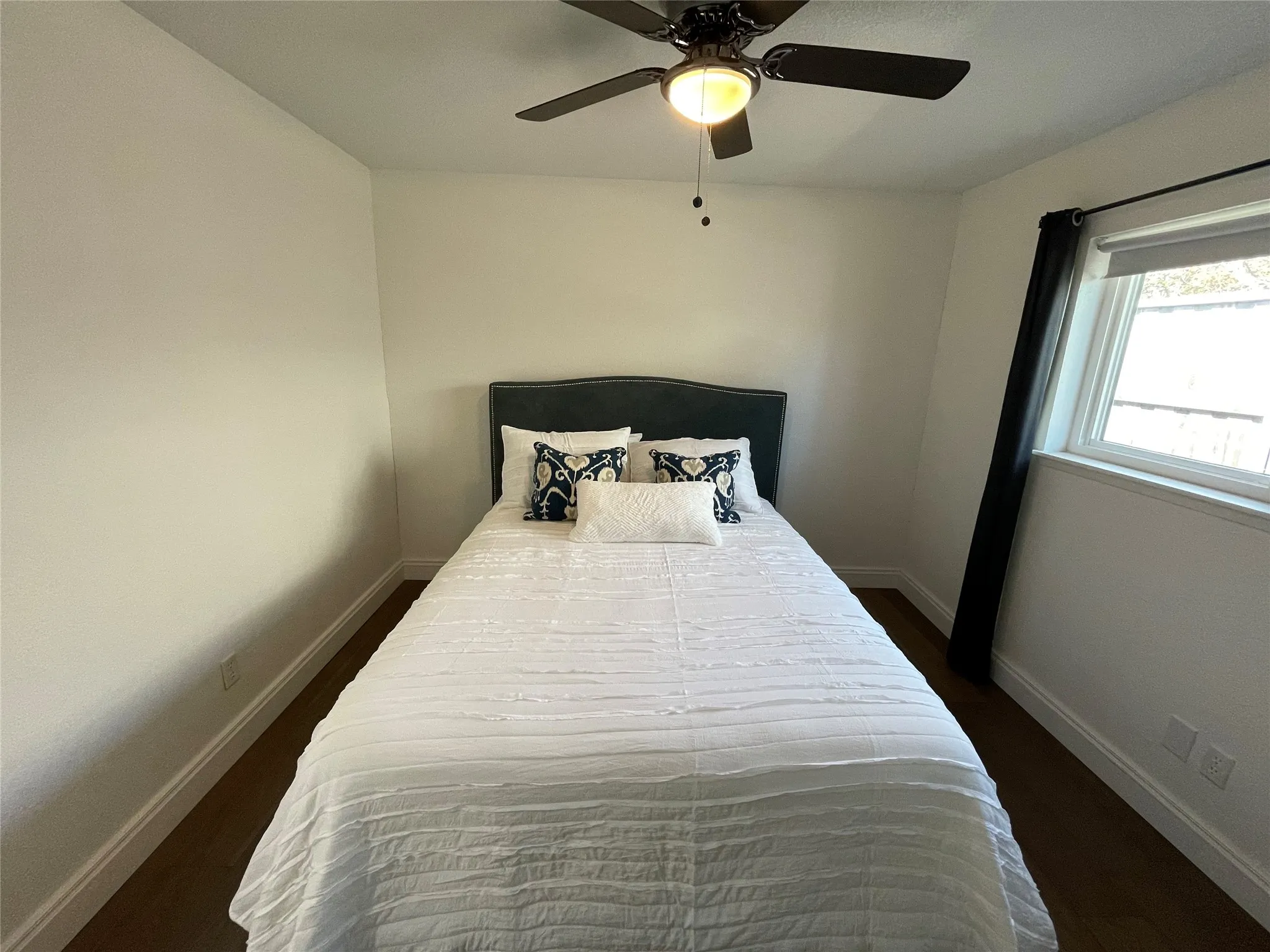 Bedroom featuring a ceiling fan with integrated lighting, wood-finish flooring, and white baseboards