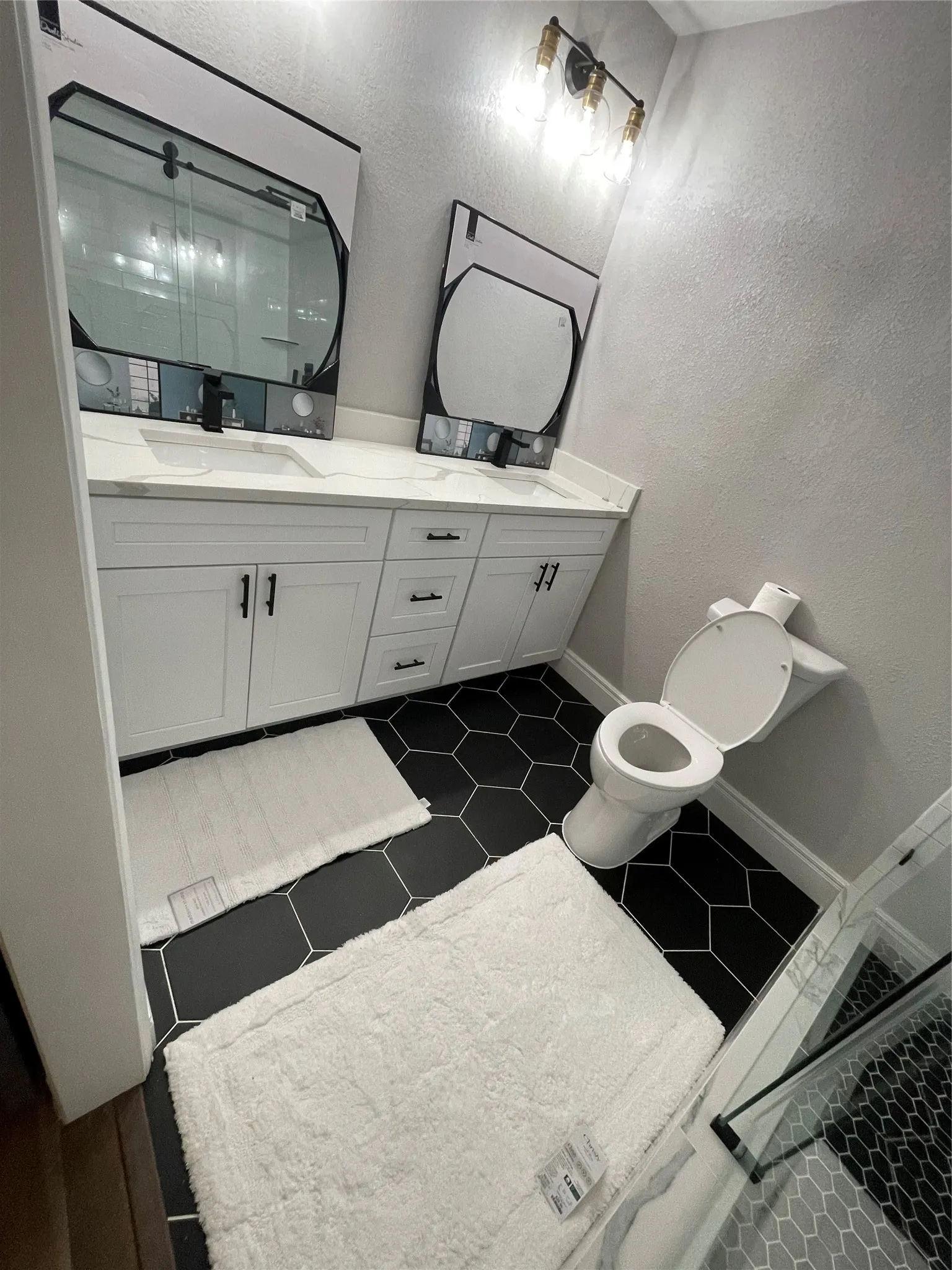 Dual vanity with white shaker-style cabinetry, white countertops, and matte black hardware