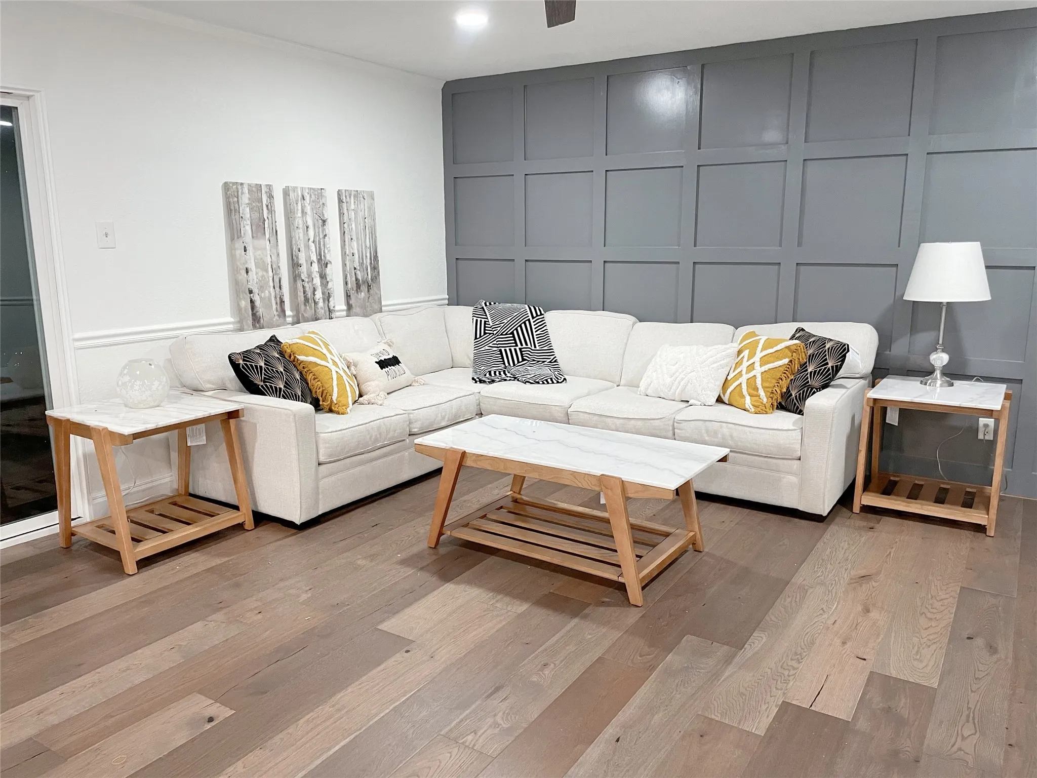 Spacious living area featuring wide plank wood-finish flooring, a paneled accent wall, crown molding, and recessed lighting