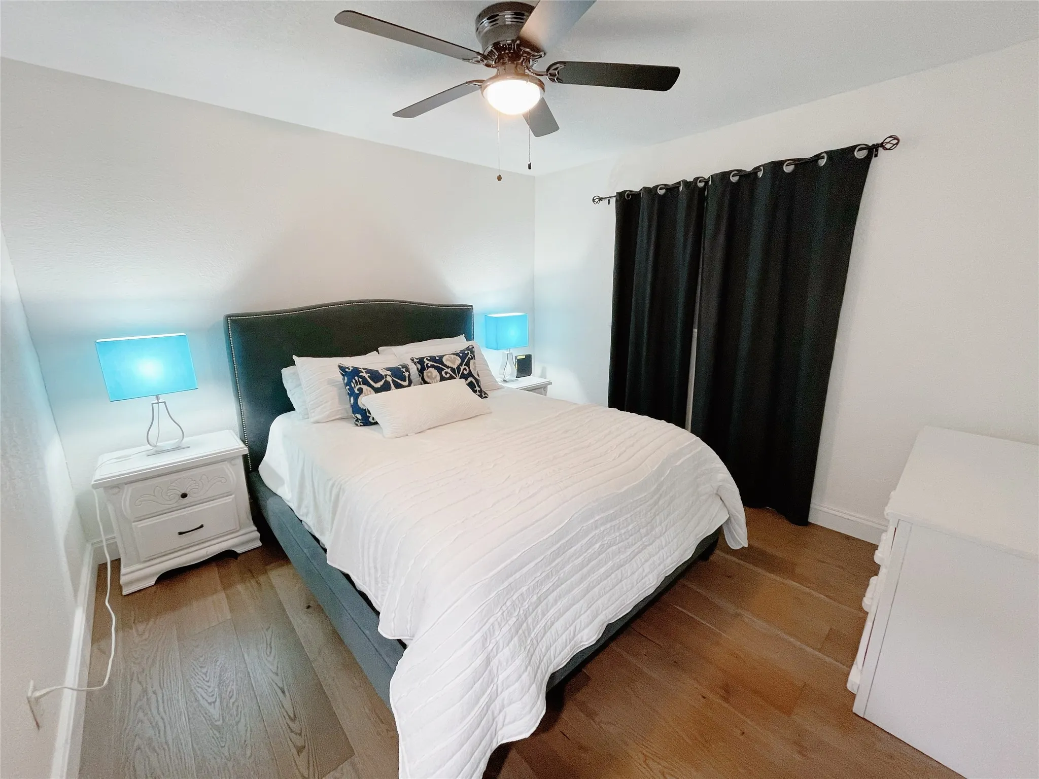 Bedroom featuring wood-finish flooring, white walls, and a ceiling fan with integrated lighting