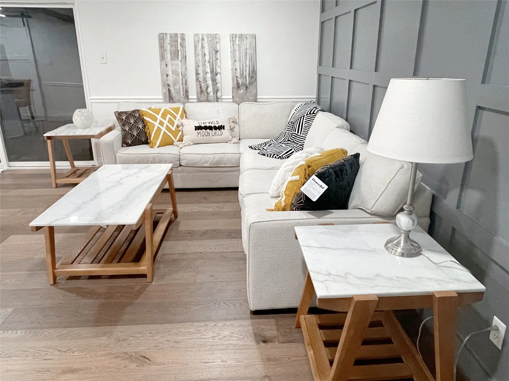 Living area featuring wood-finish flooring, a decorative panel accent wall, and white baseboards