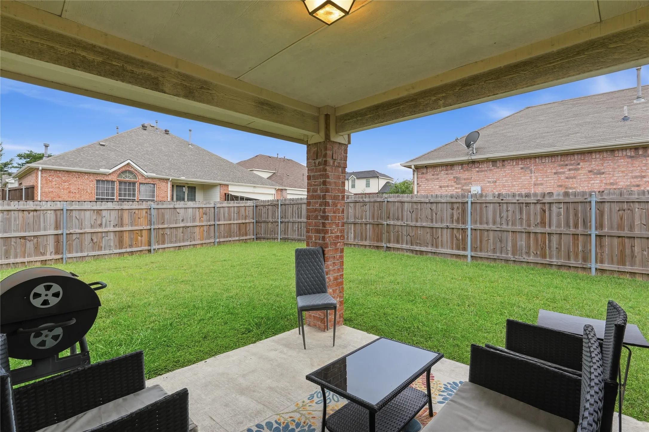 Covered patio with a concrete slab, overhead lighting, and brick column accents