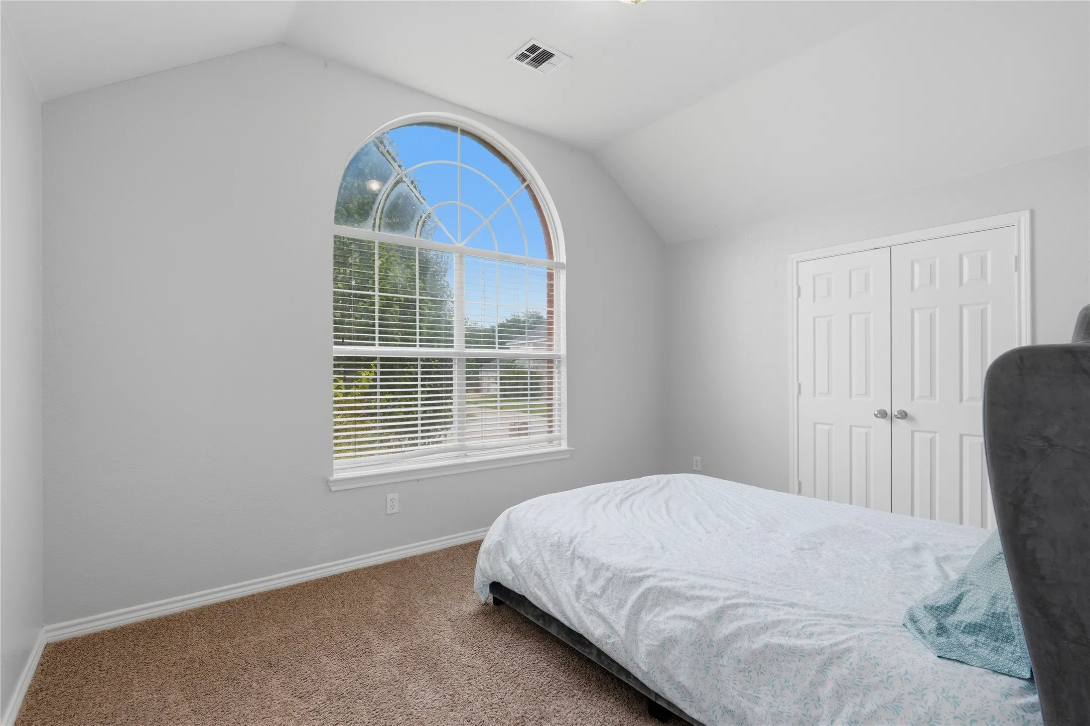 Arched window with gridded upper pane and horizontal blinds