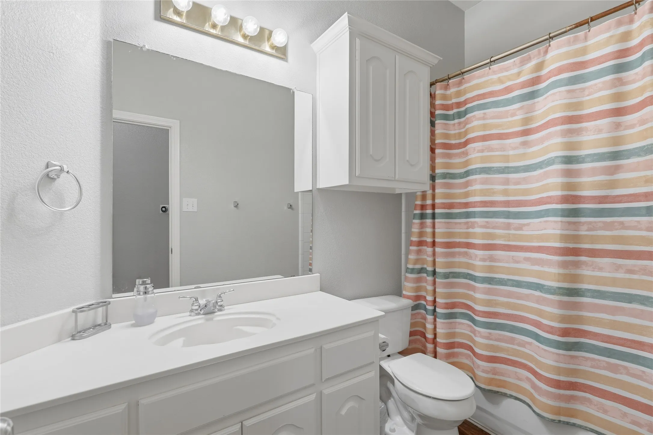 Bathroom vanity with an integrated sink, polished chrome faucet, and overhead bar lighting