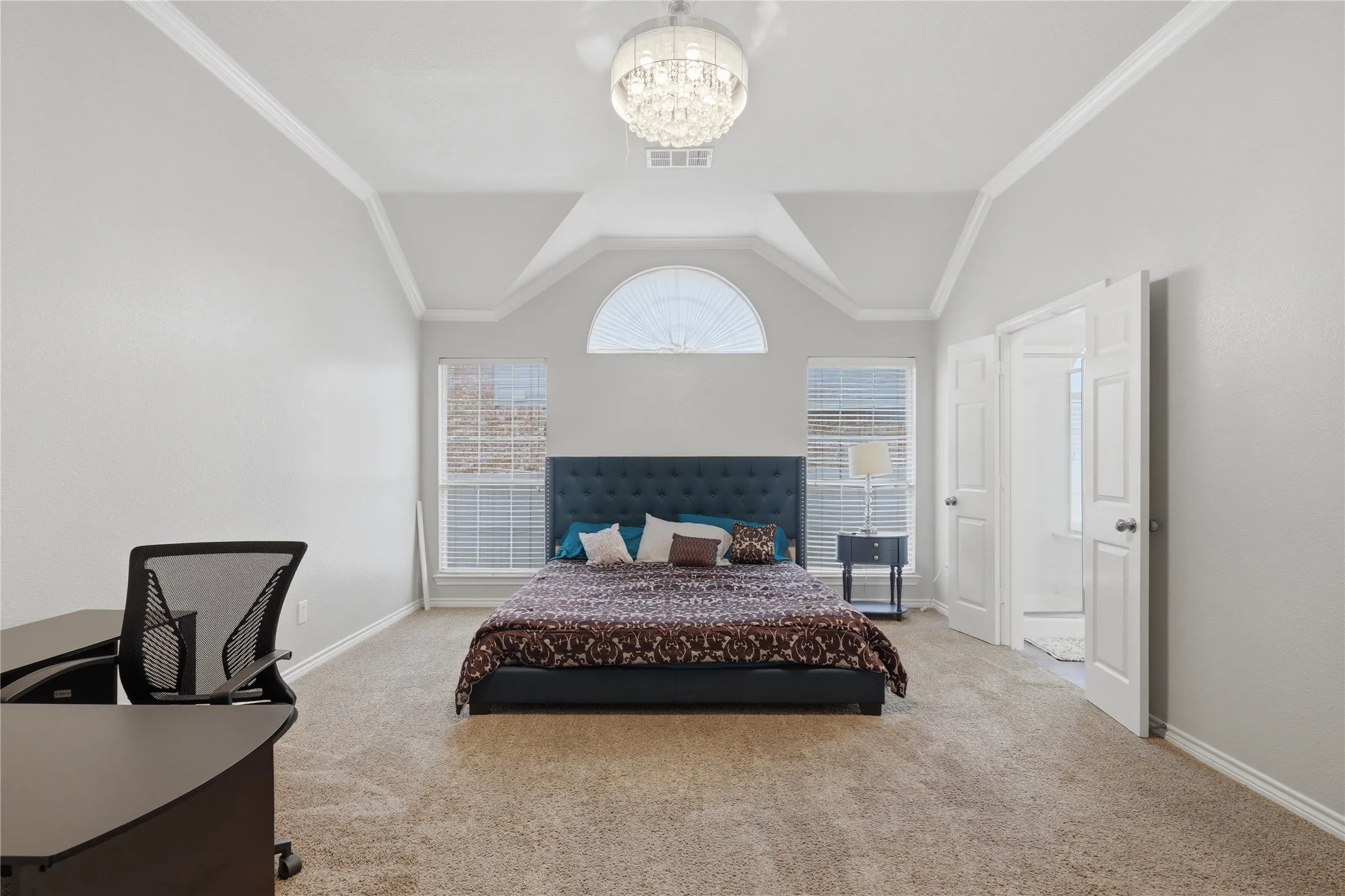 Spacious room featuring vaulted ceilings, a prominent arched window, and two large windows with blinds