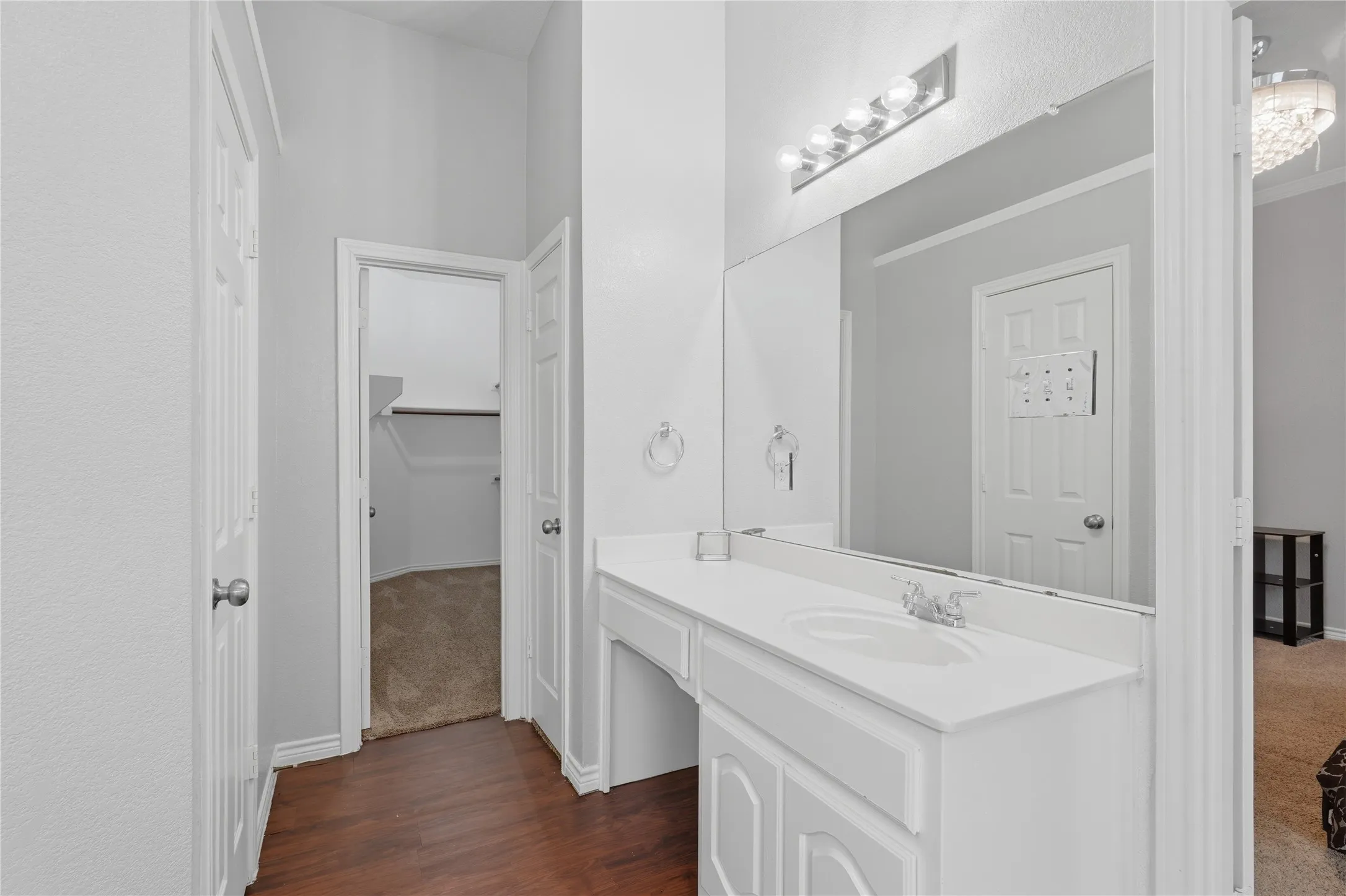 Bathroom vanity featuring an integrated sink with chrome faucet, a large wall-mounted mirror, and a 5-bulb vanity light fixture