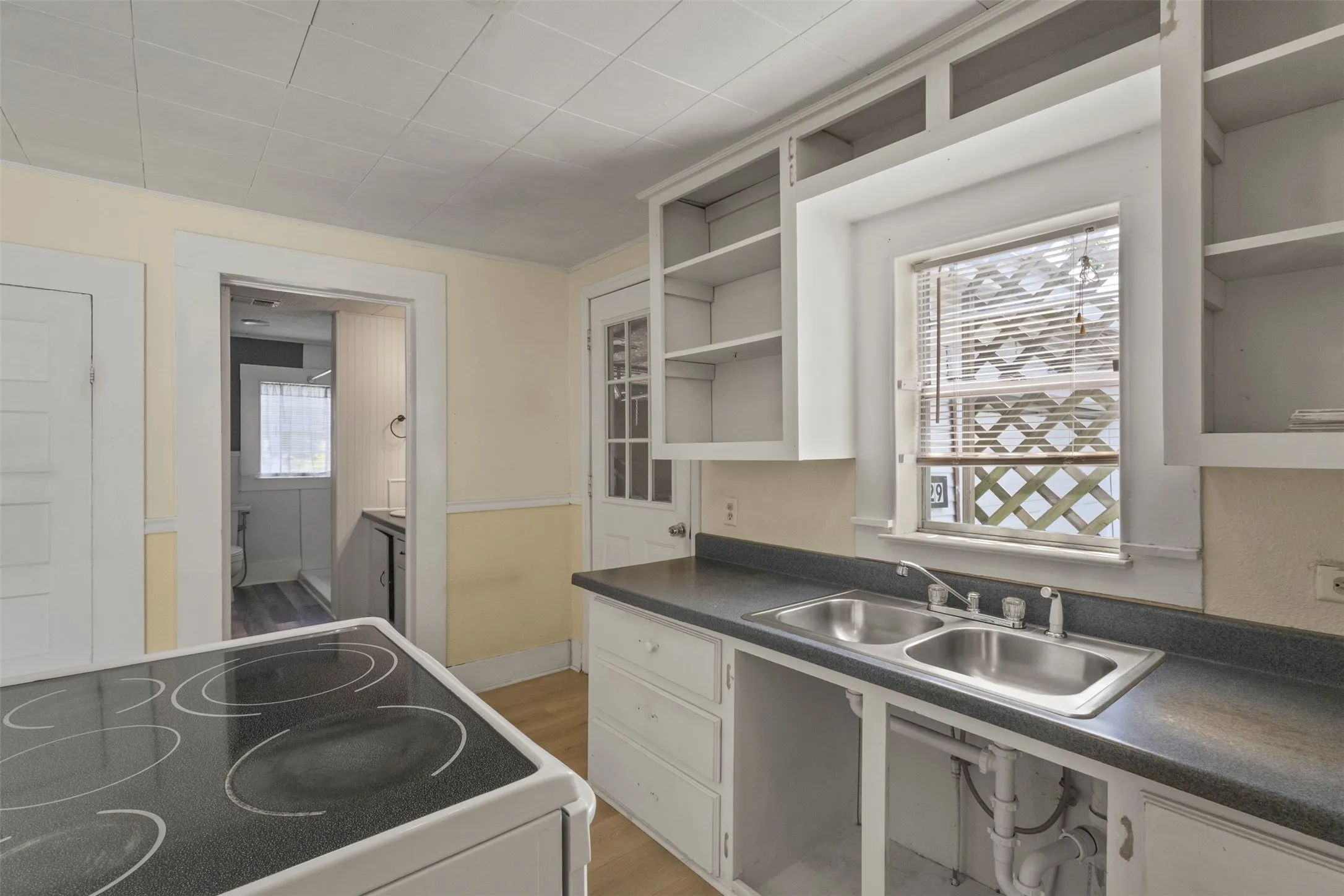 Kitchen featuring white cabinetry, a double basin stainless steel sink, black countertops, and a built-in stovetop