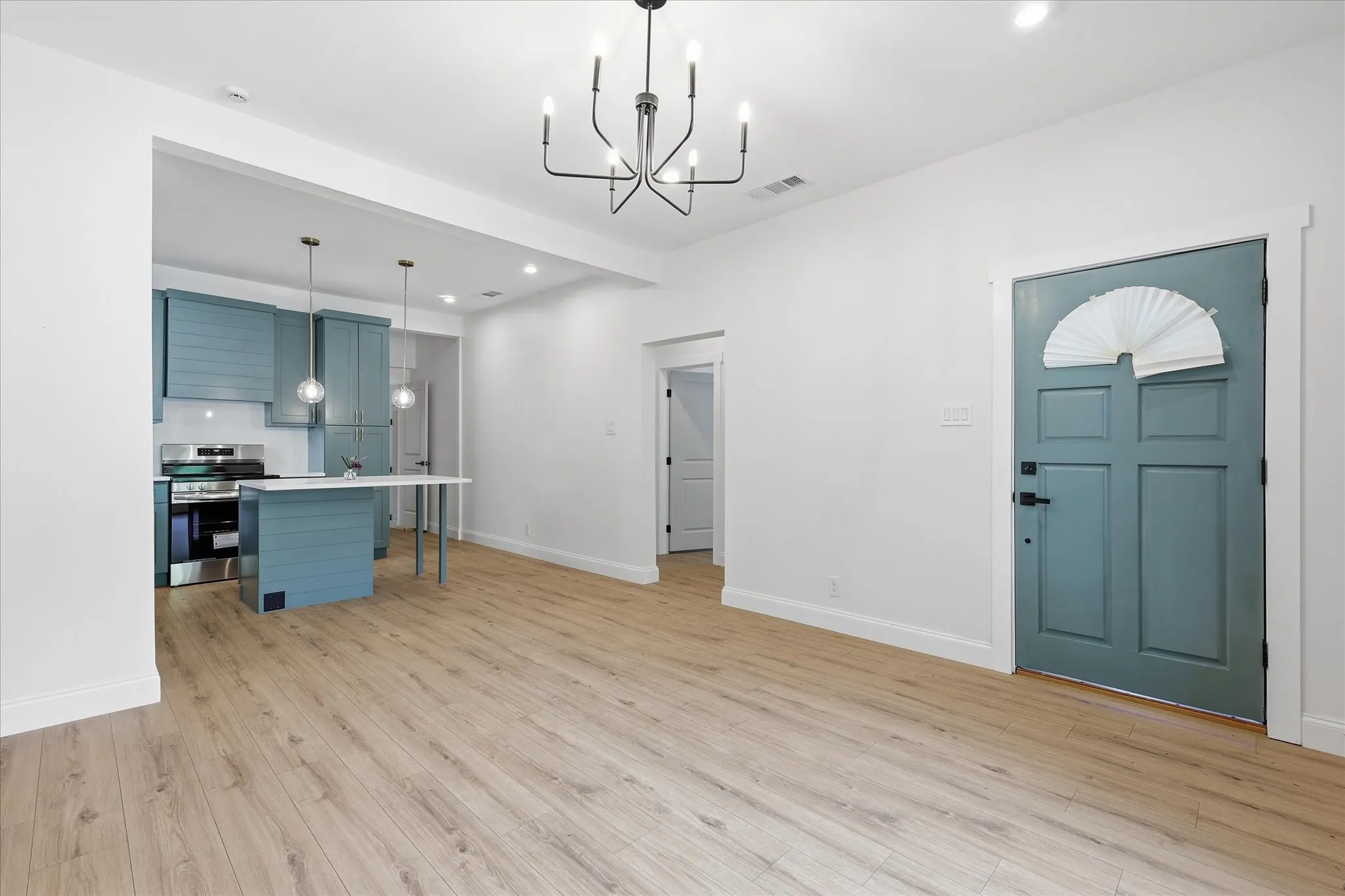 Open-concept living space featuring wood-finish flooring, a modern chandelier, and recessed lighting