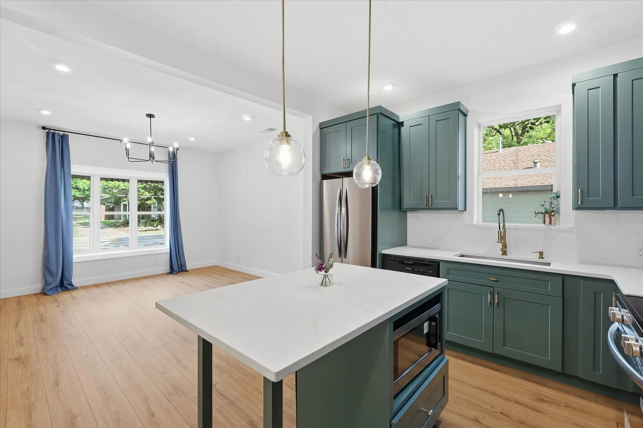 Modern kitchen featuring teal cabinetry, stainless steel appliances, and a central island with a built-in microwave