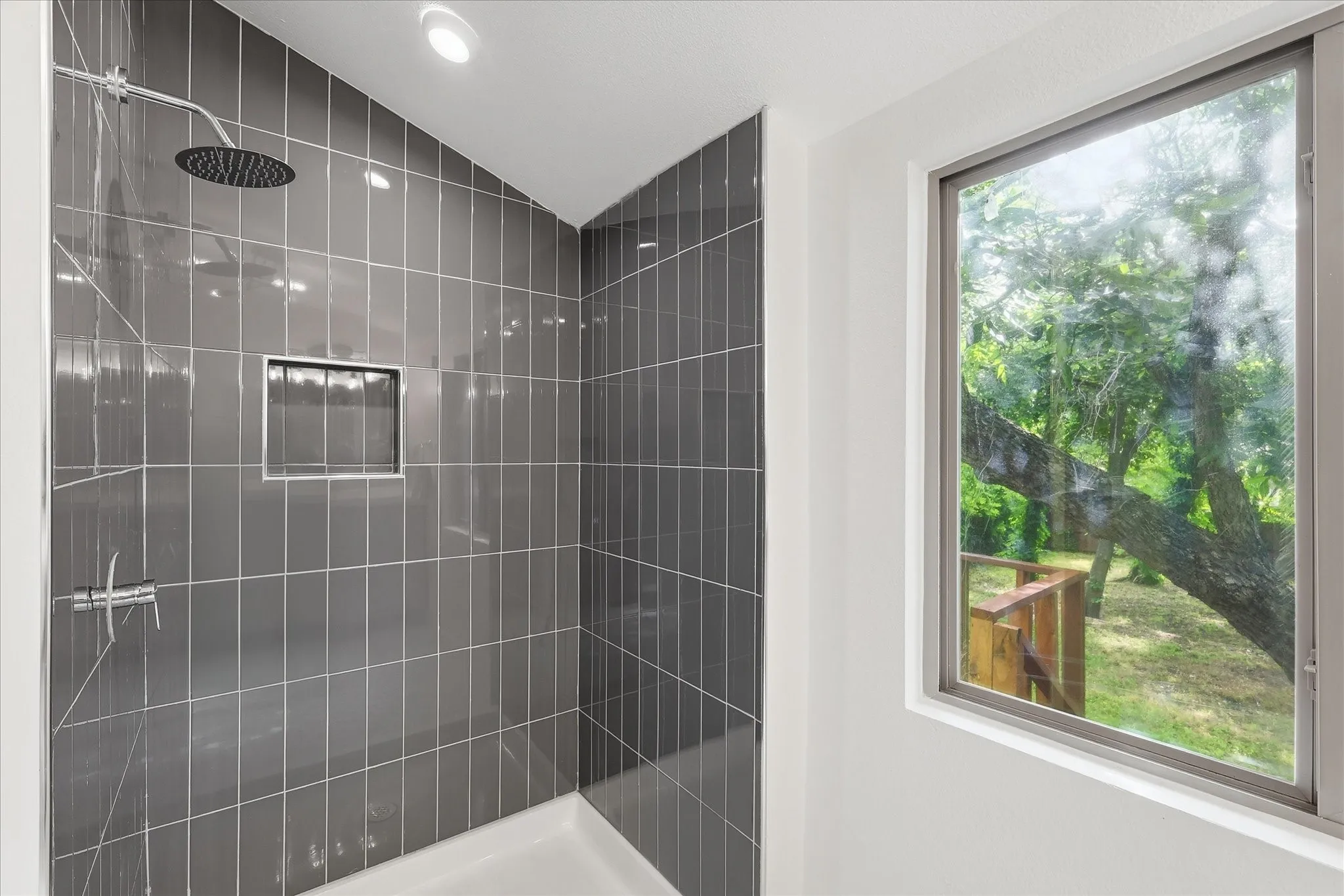 Contemporary shower enclosure featuring dark gray vertical tile, a recessed niche, and a rain showerhead