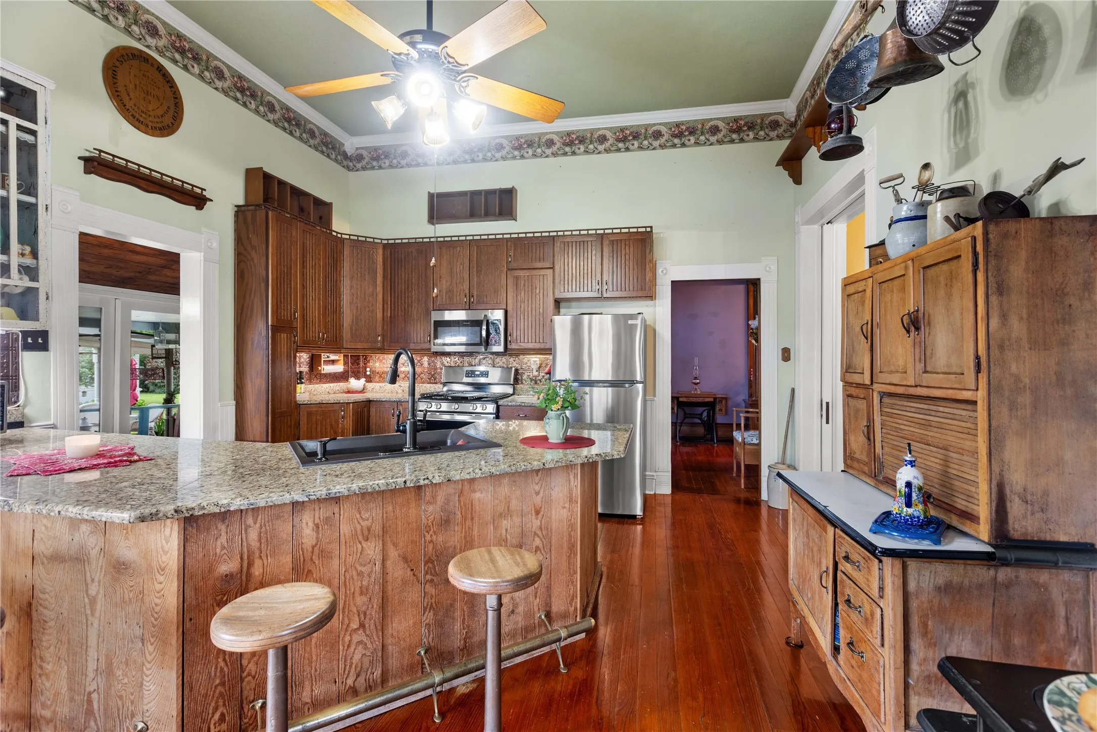 Kitchen featuring wood-finish flooring, a ceiling fan with integrated lighting, and a peninsula with a stone countertop