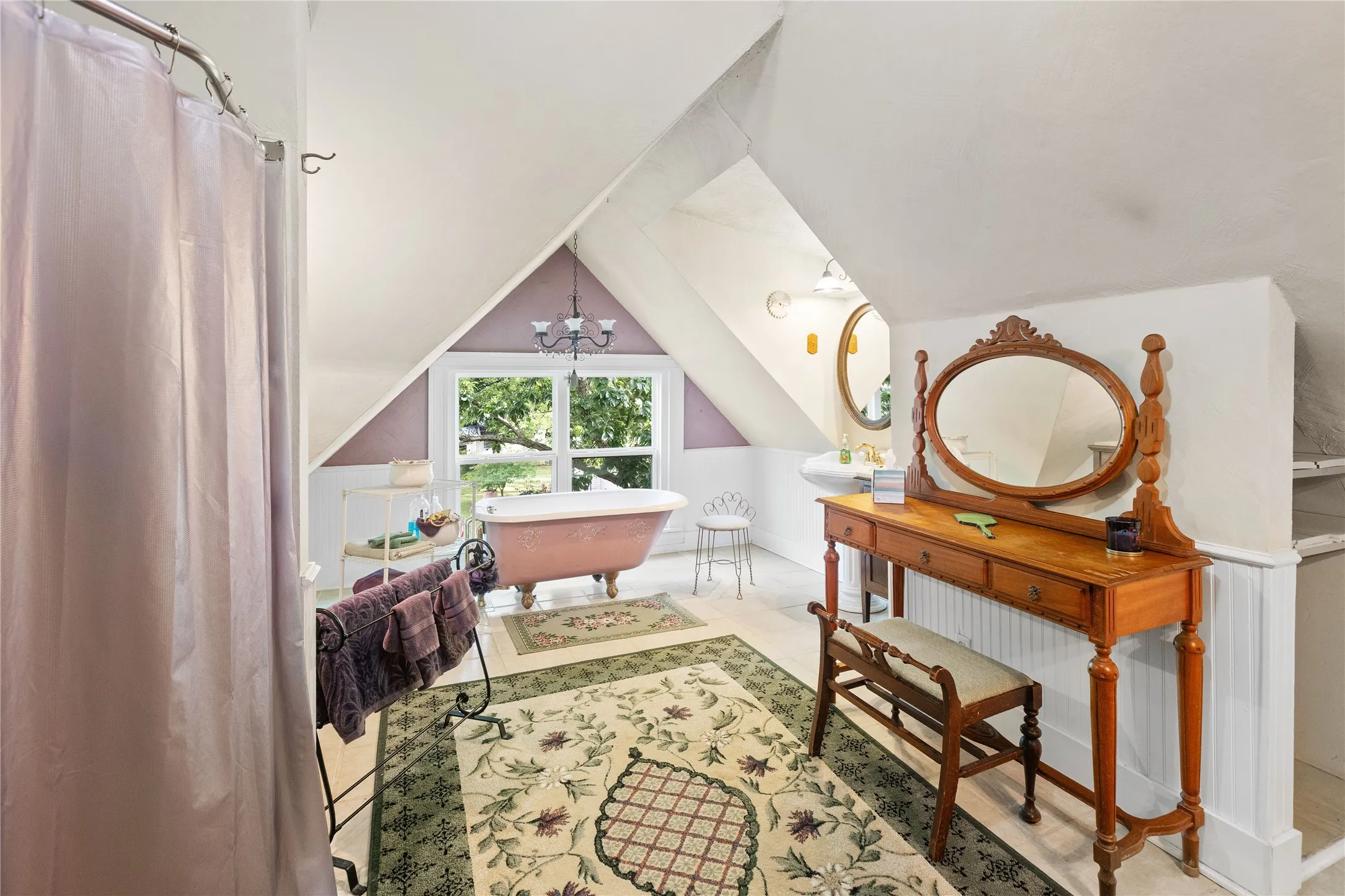 Upstairs primary bathroom featuring a clawfoot tub, white wainscoting, and a pedestal sink