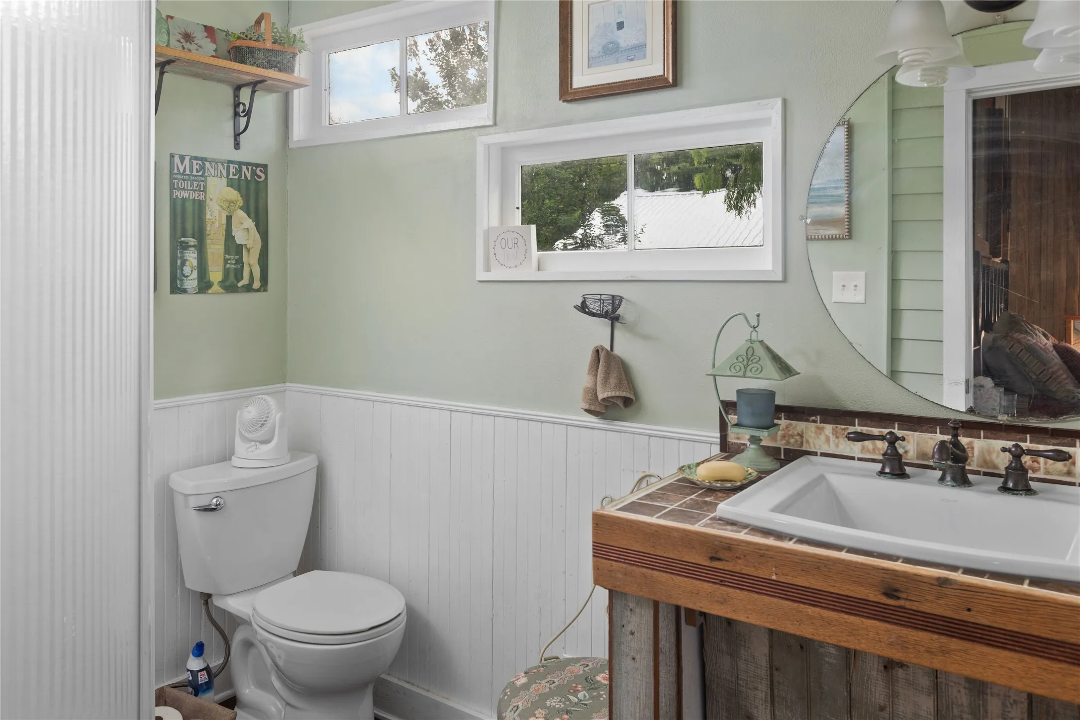 The Nest (3rd dwelling) Bathroom featuring a white toilet, white wainscoting, and a wood-finish vanity with a tile countertop