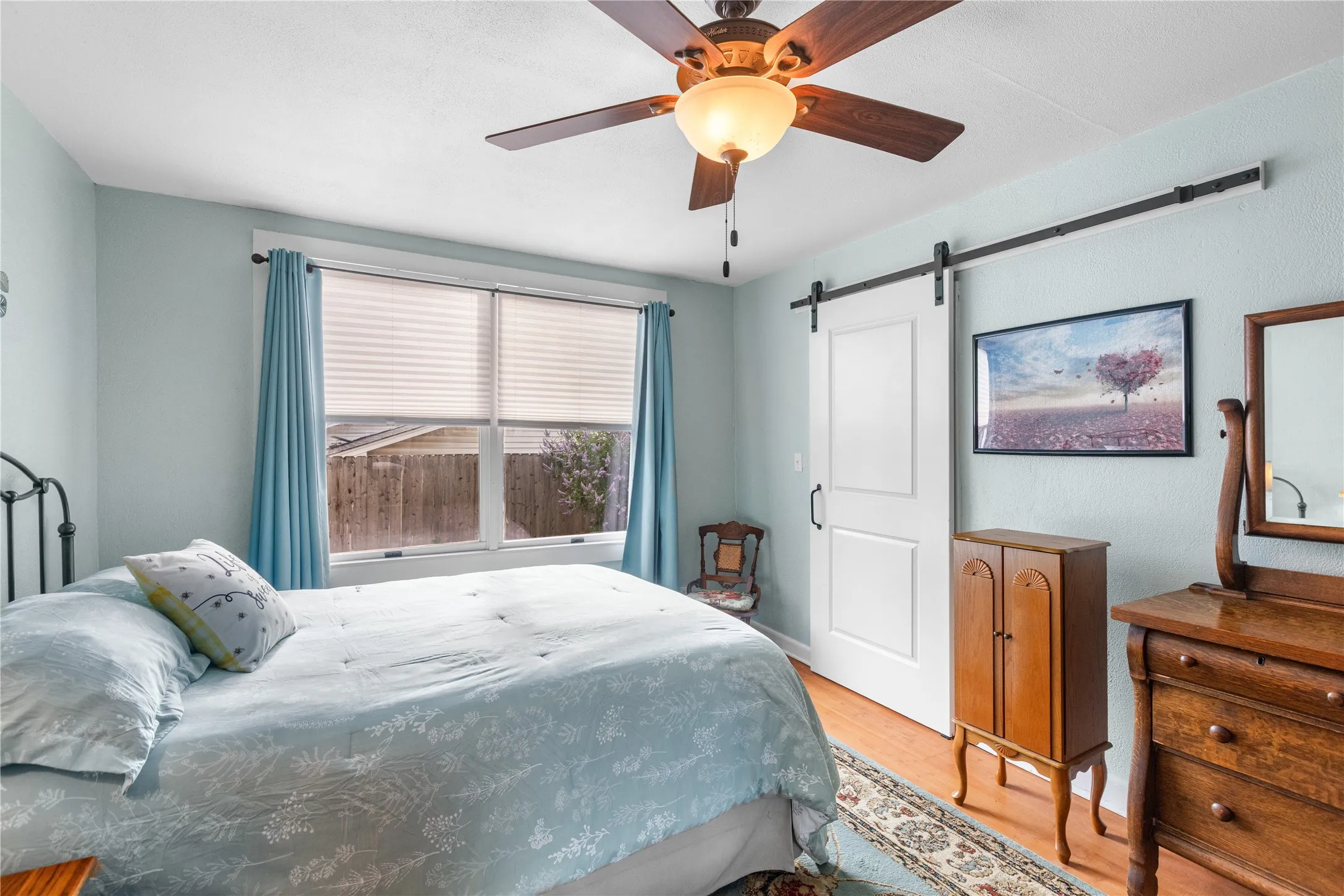 Downstairs primary bedroom featuring wood-finish flooring and light blue walls