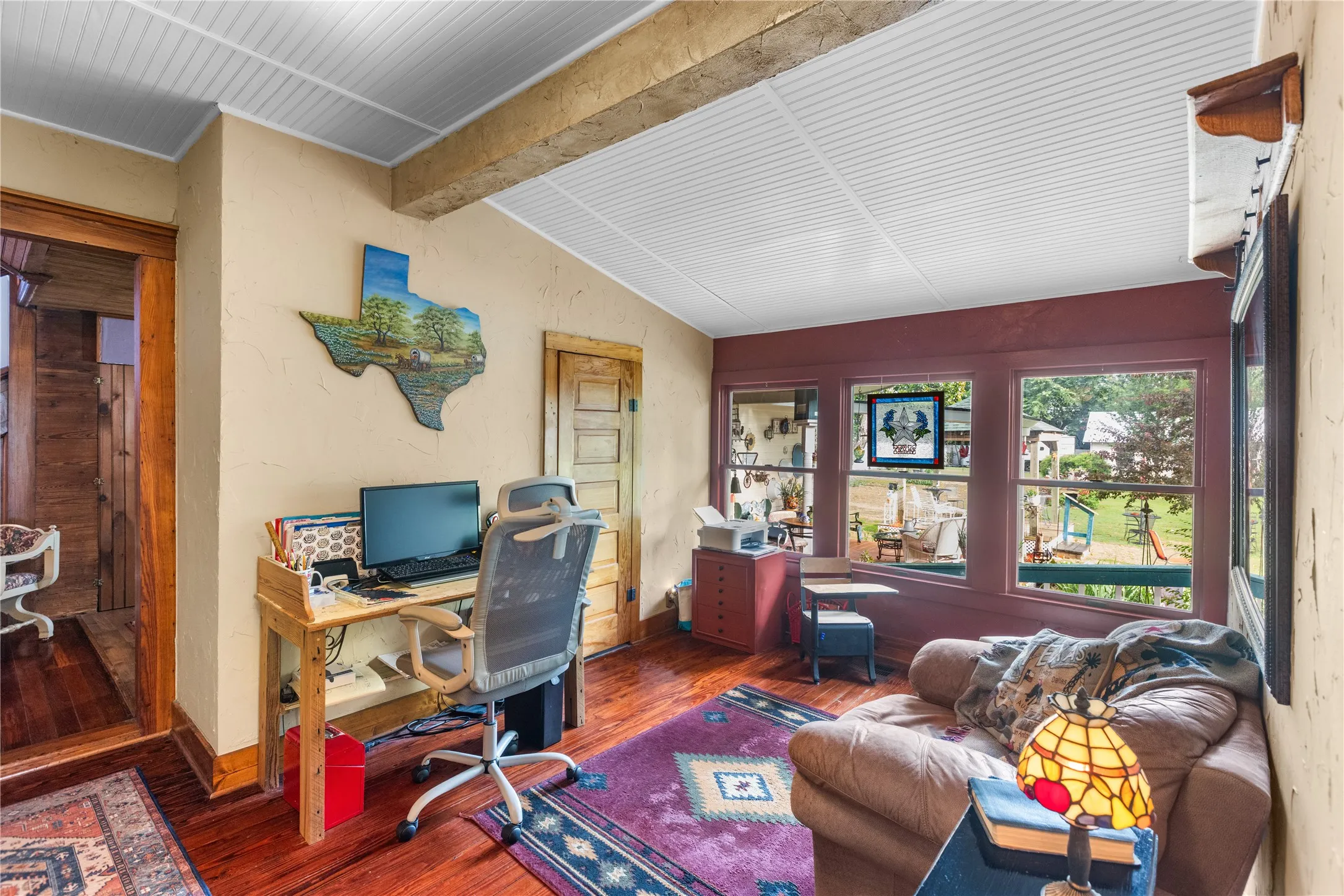 Room featuring wood-finish flooring, a white beadboard ceiling with exposed wood beam, and light-toned walls