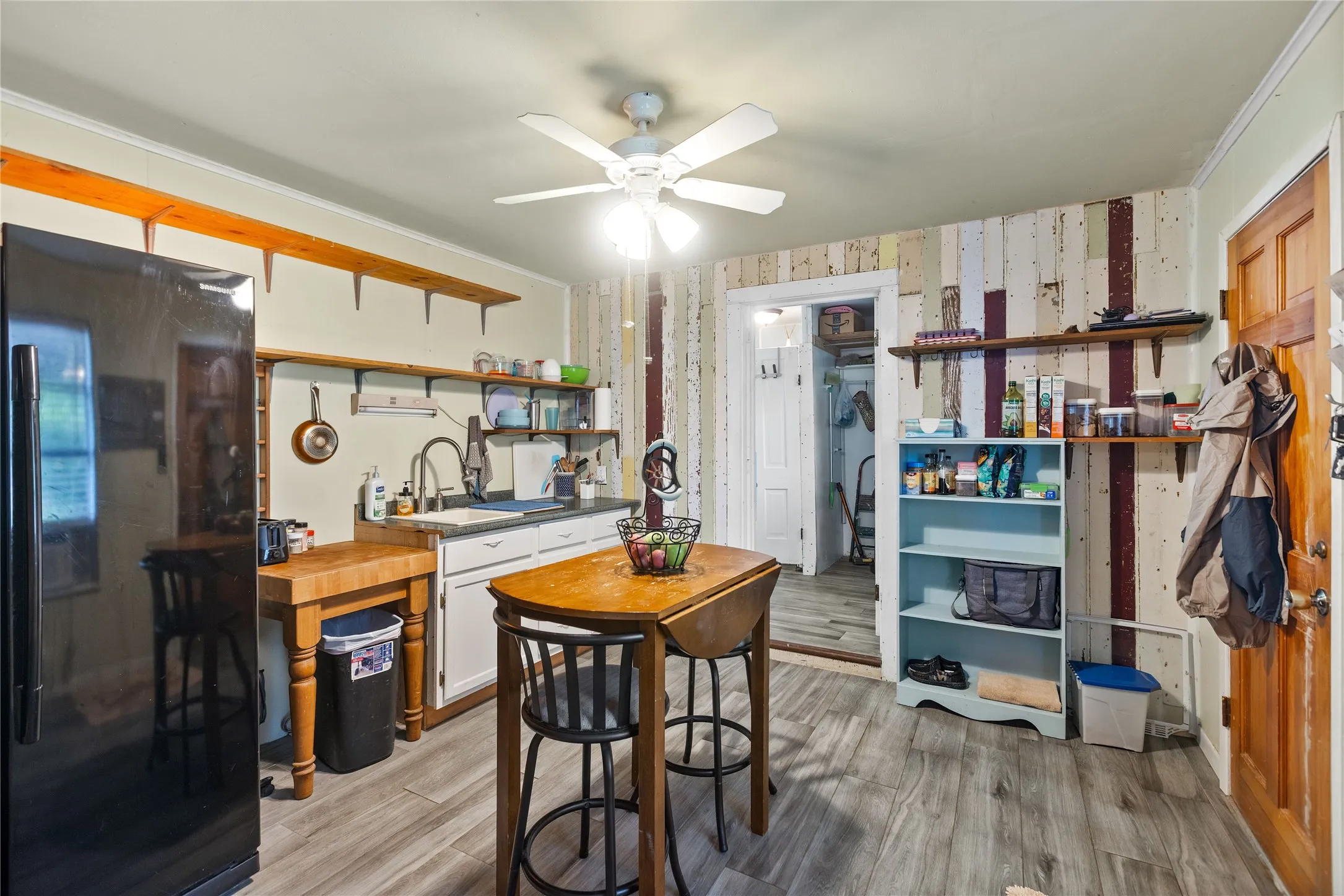 Dwelling 2 Kitchenette featuring wood-finish flooring, white cabinetry with a single-basin sink, butcher block island, open shelving, and a ceiling fan light fixture
