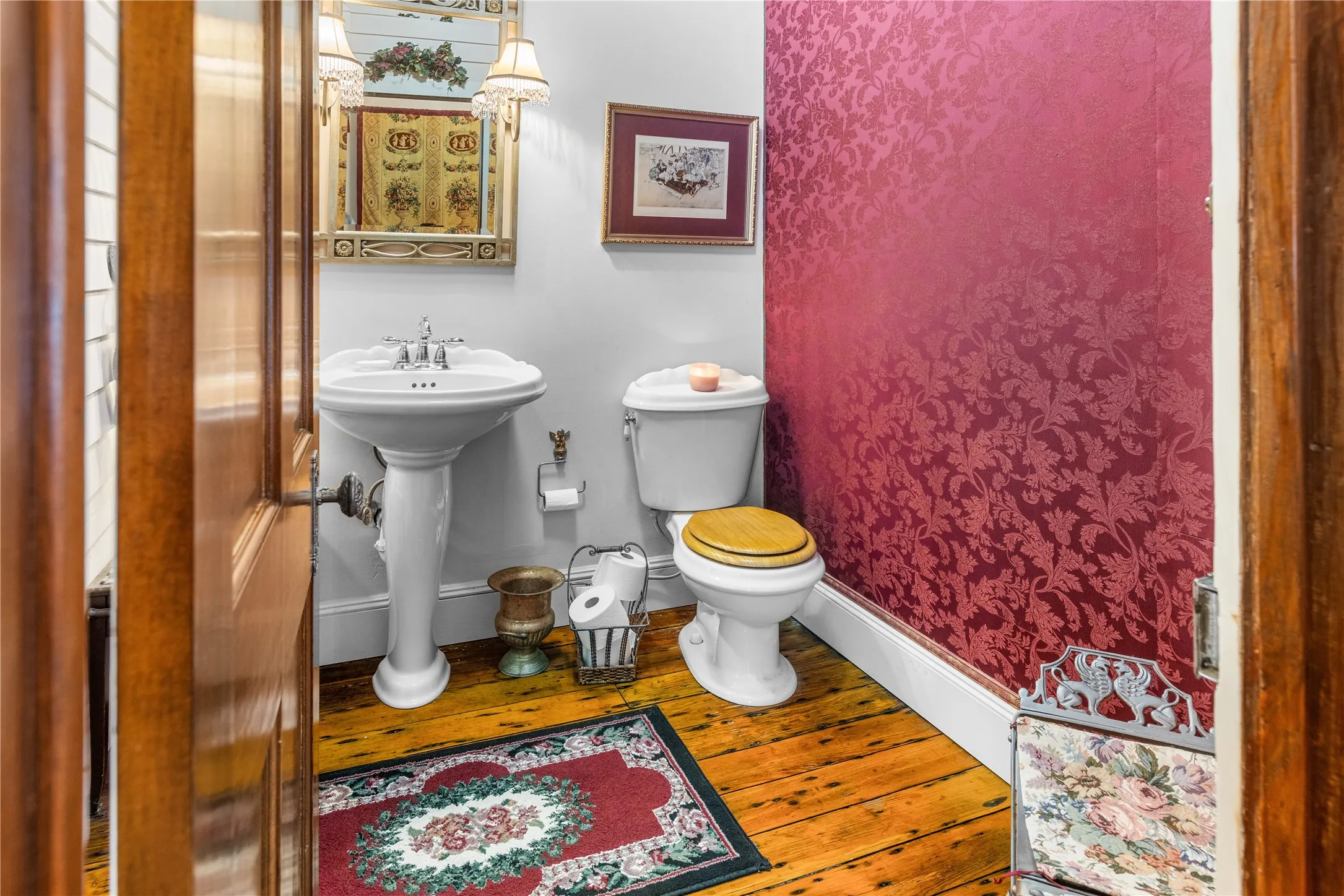 Half bath w/Pedestal sink with chrome fixtures, wood-finish flooring, and a patterned accent​​‌​​​​‌​​‌‌​‌‌​​​‌‌​‌​‌​‌​​​‌​​ wall