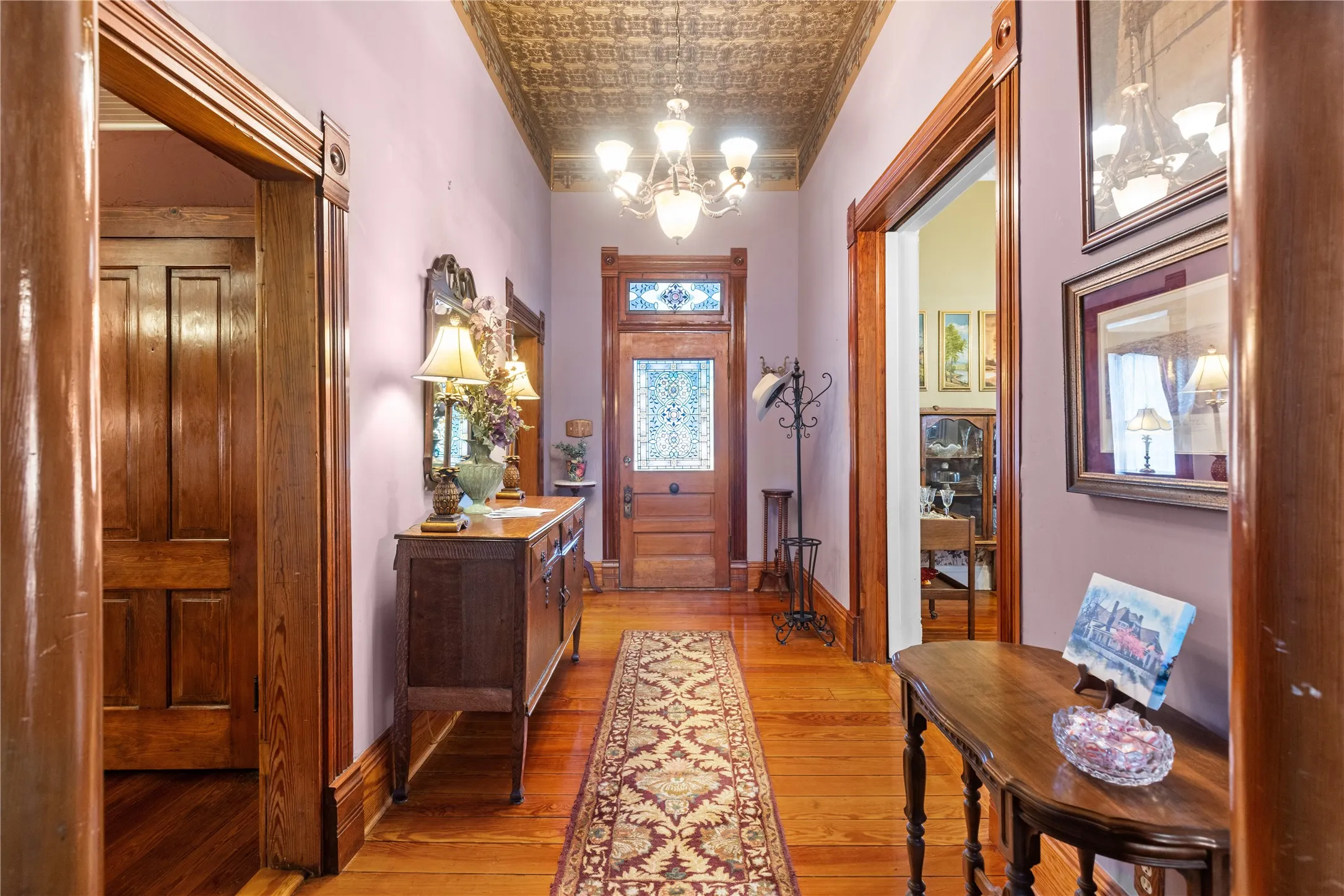 Hallway featuring wood-finish flooring, a decorative ceiling, and rich wood trim around doorways